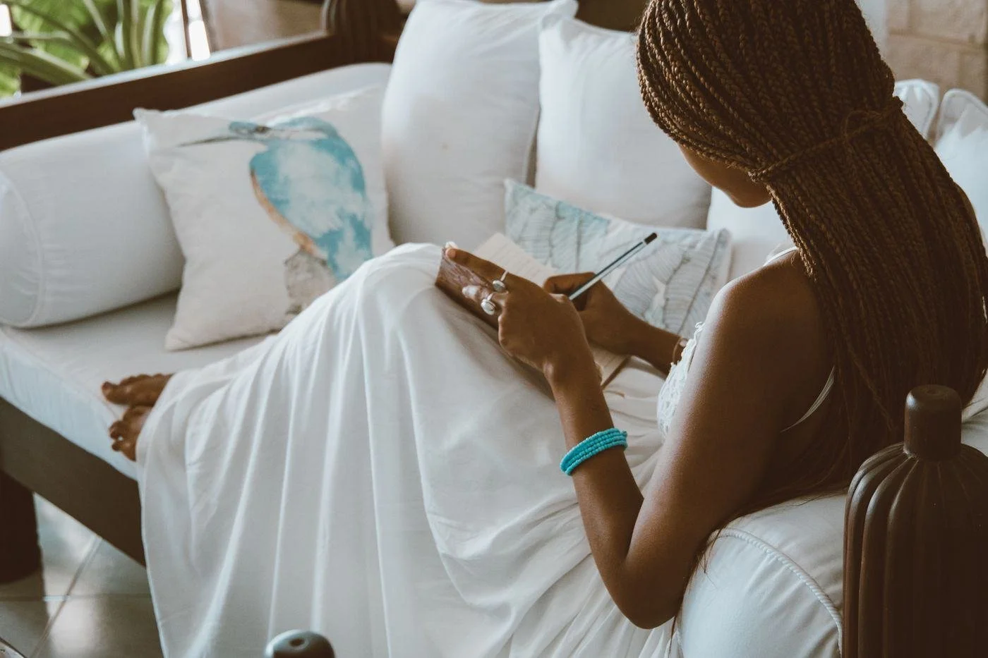 A woman writing in a notebook on her sofa
