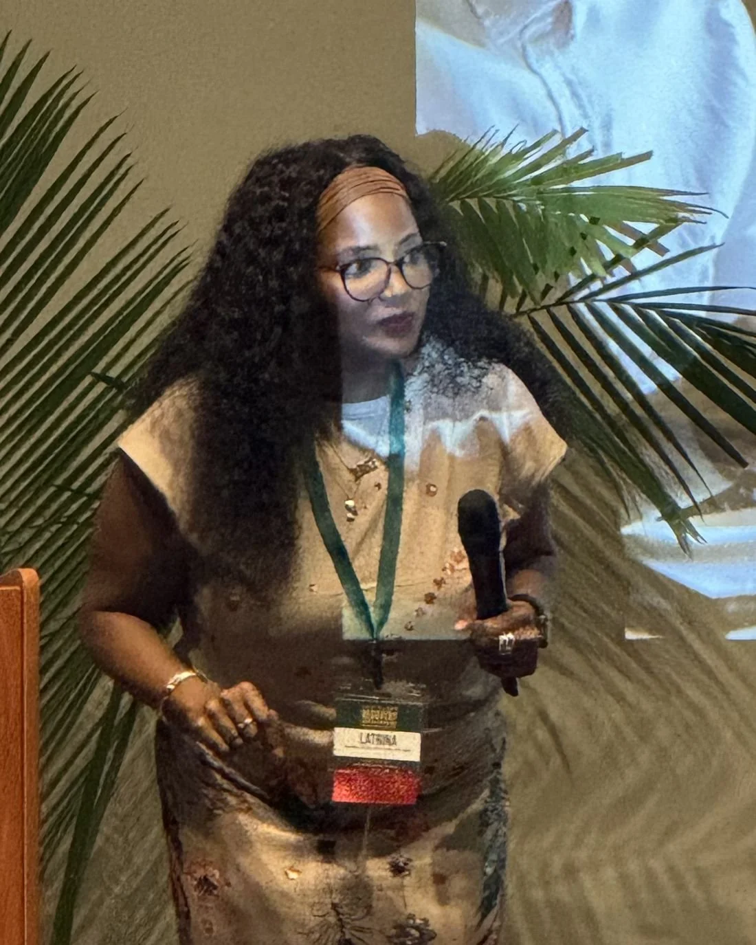 Latrina speaking into a microphone on stage at a conference