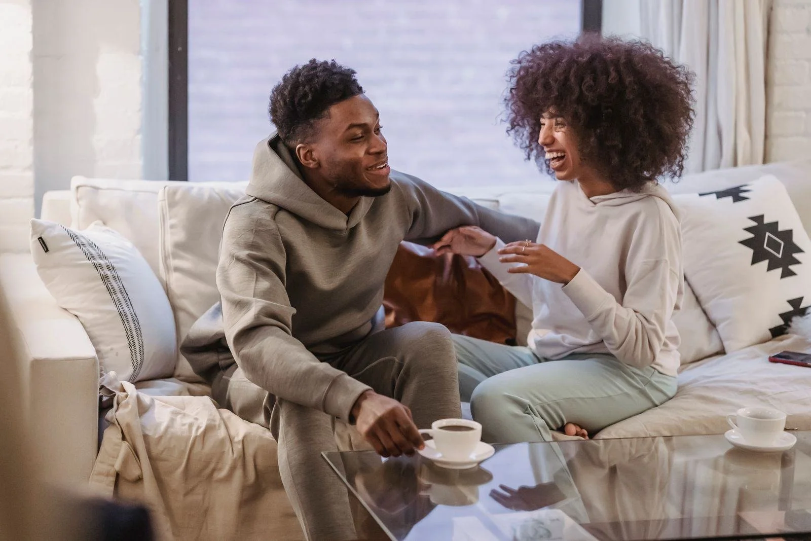 A Black couple laughing together on the couch at home