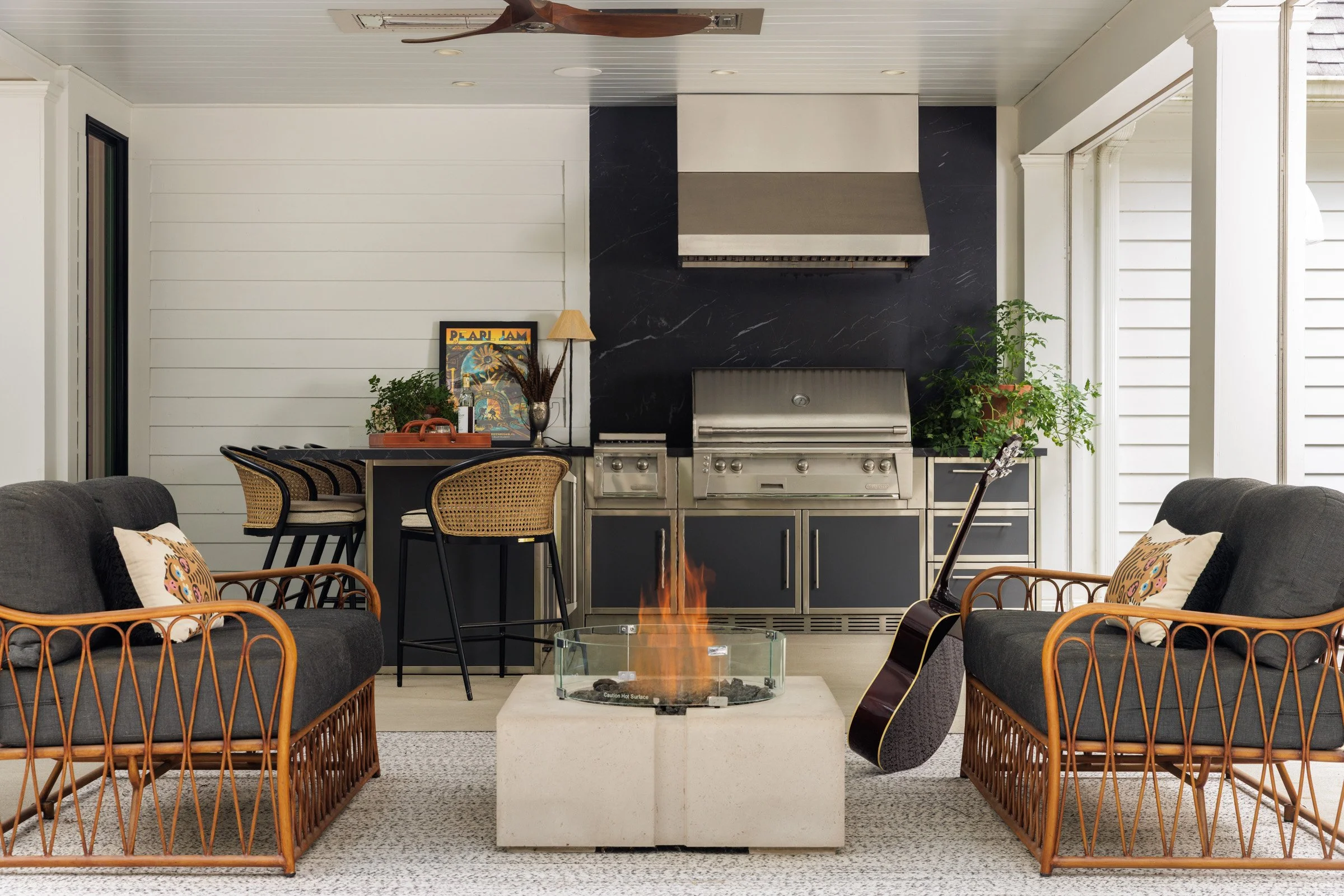 Treesdale covered outdoor kitchen with rattan lounge chairs, a fire table and a guitar