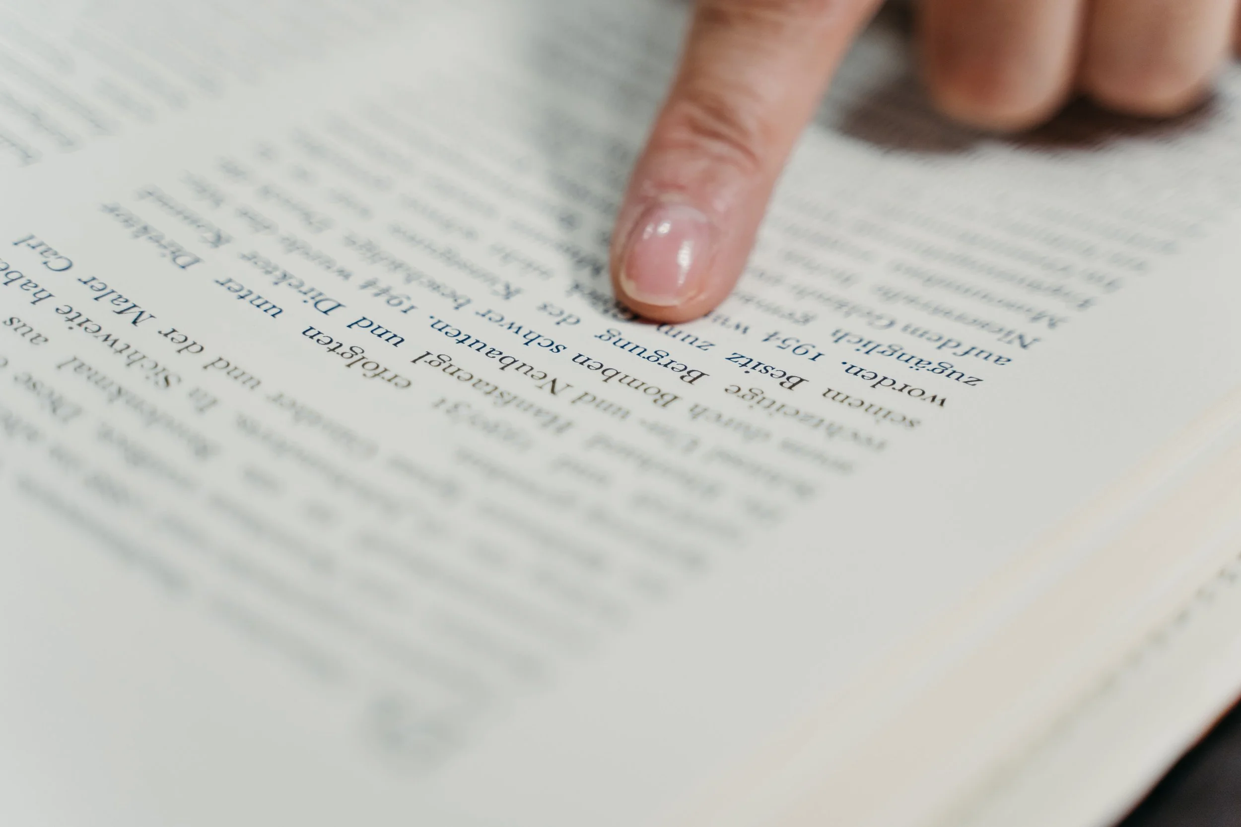Ein Deutsches Buch in Nahaufnahme und ein Finger zeigt auf ein Wort.