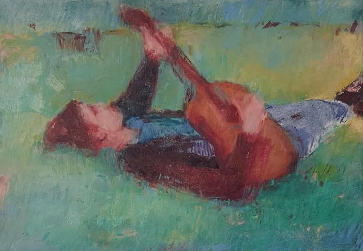 a man laying in the grass playing the guitar 