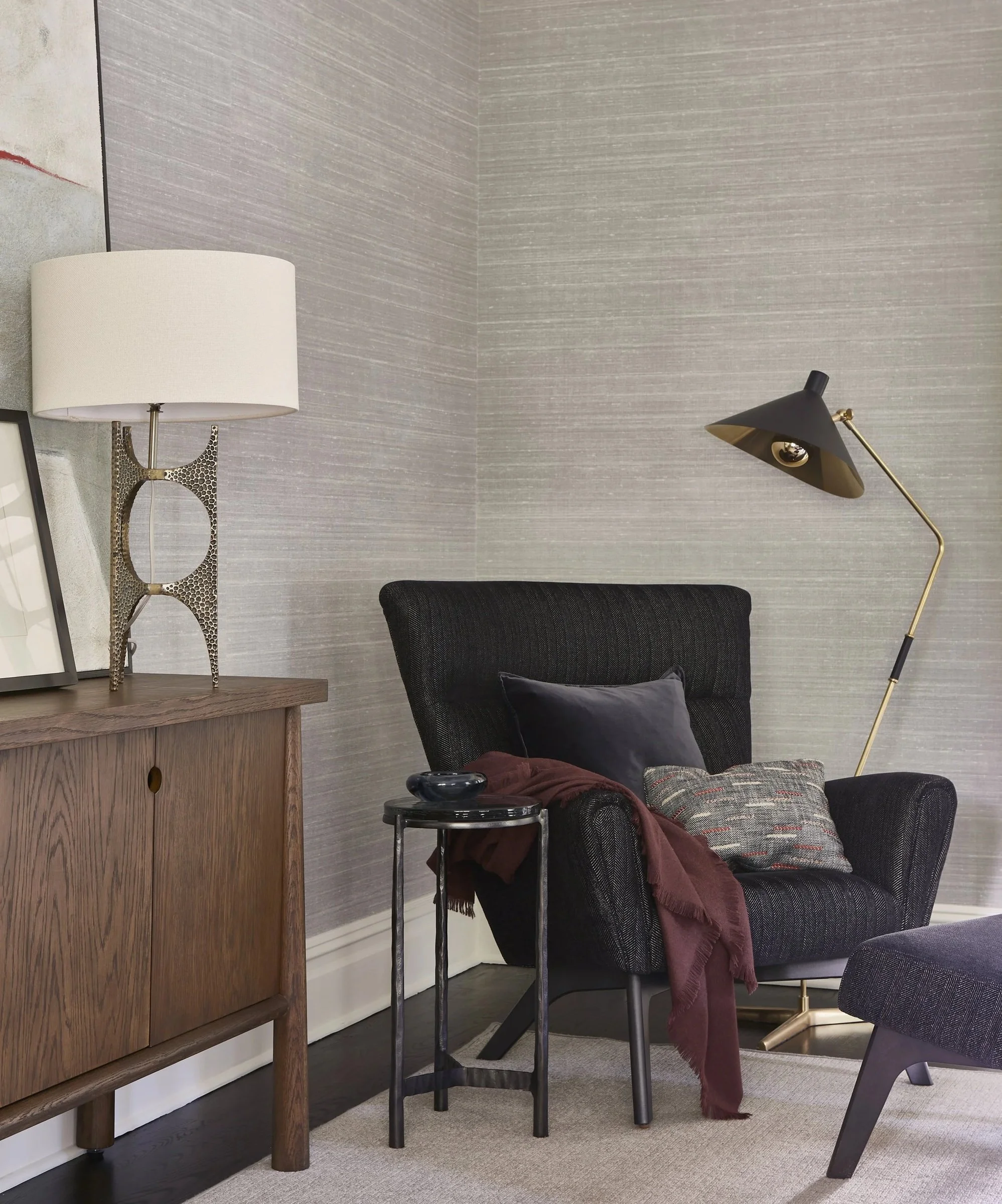 Sitting area with a dark armchair, floor lamp and wood cabinet