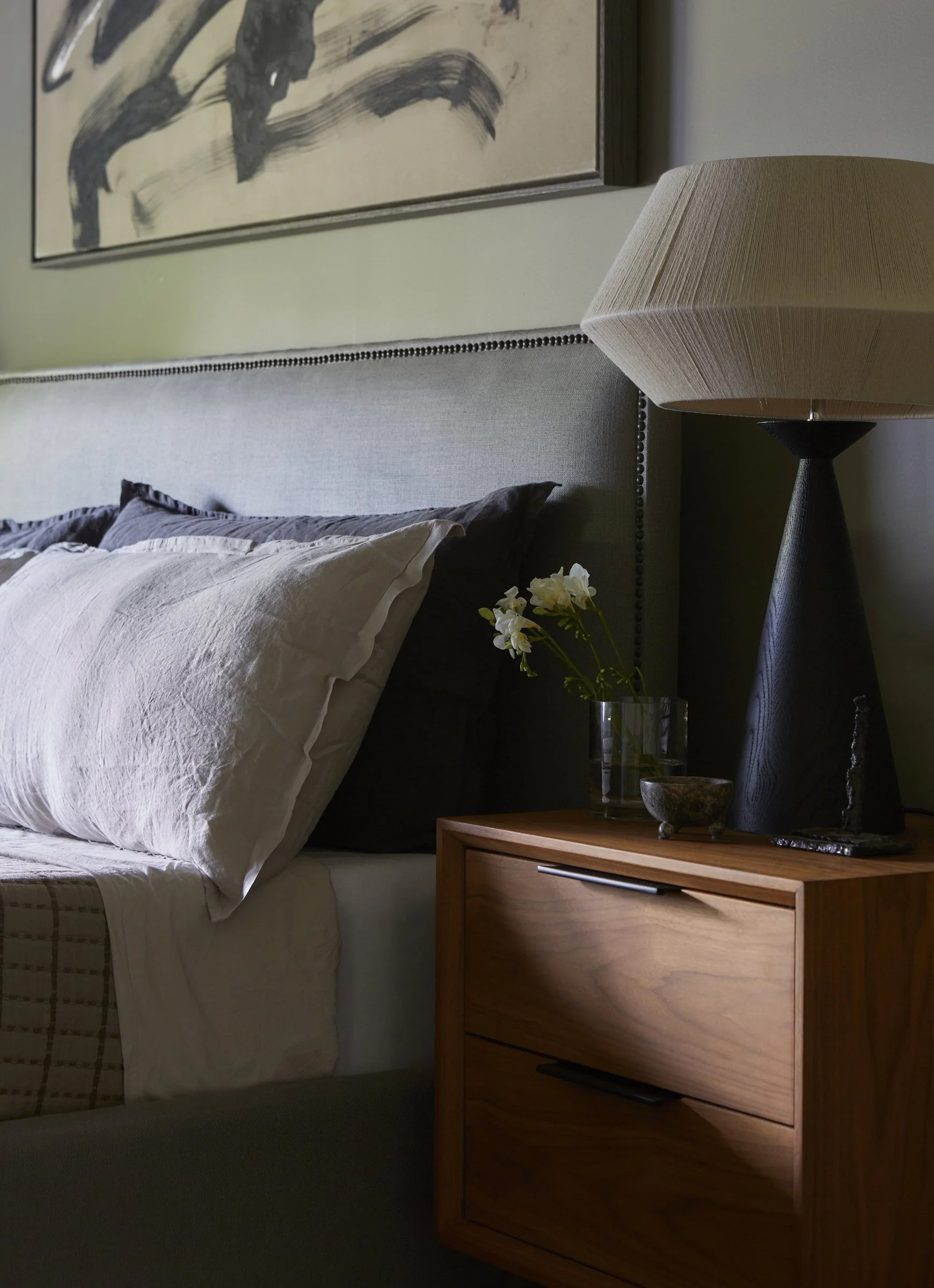 Bedroom detail with a bedside table, lamp and framed art