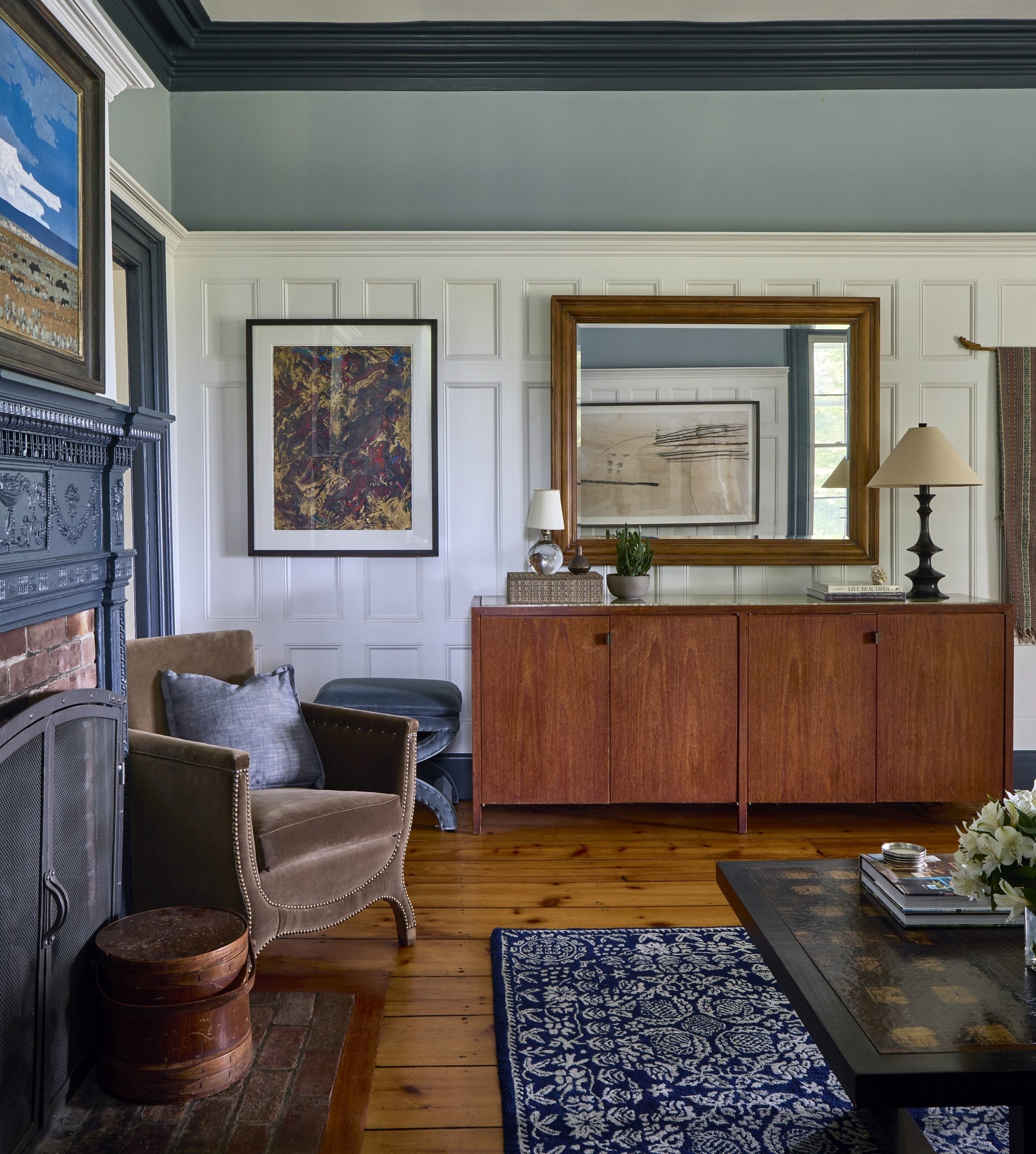 Balmville living room with layered artwork, a gilt mirror, fireplace and wood credenza