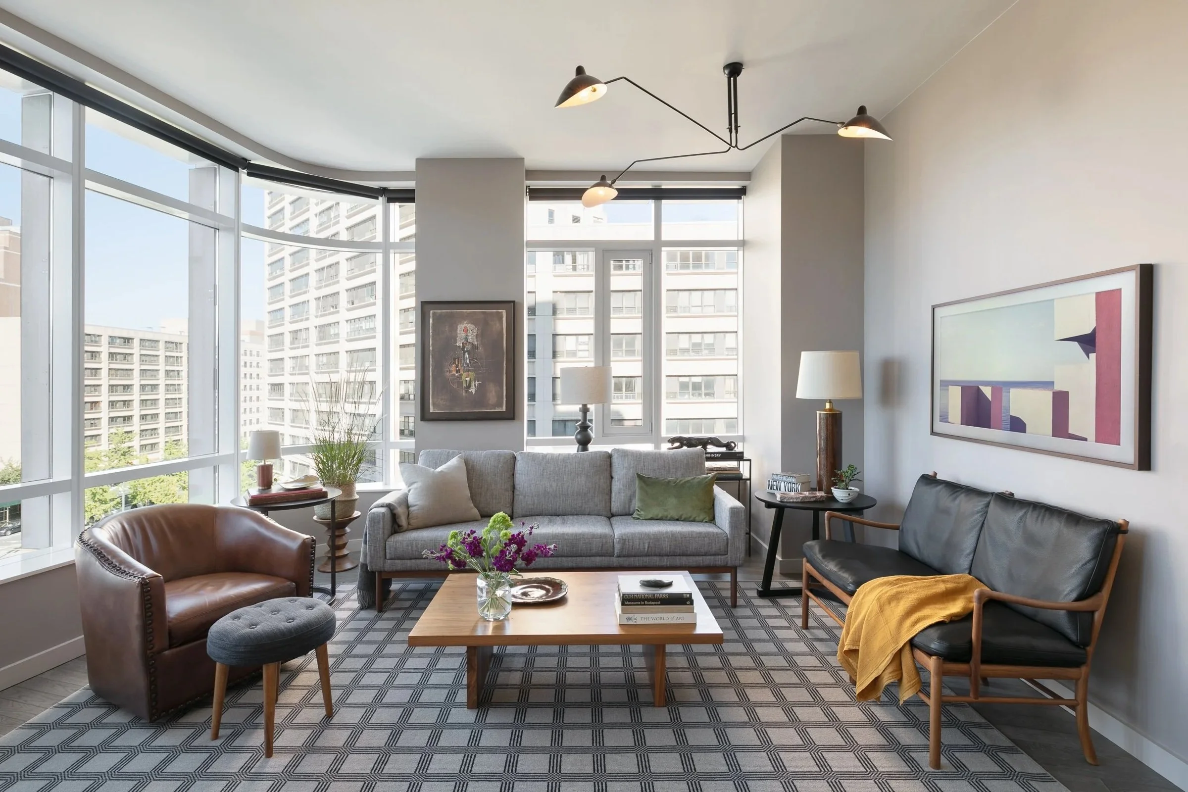 Living room with gray upholstery, wood tables and a patterned rug