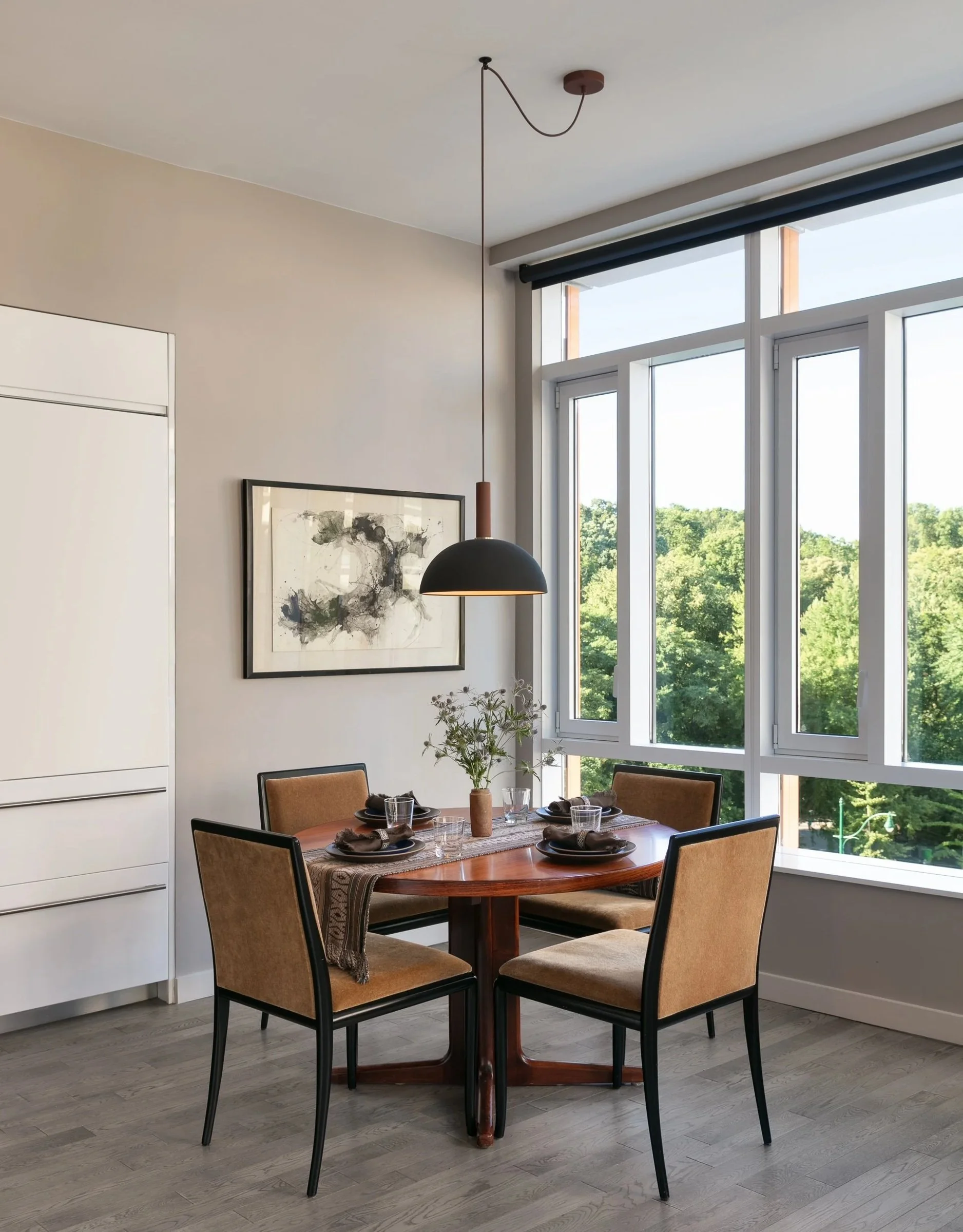 Dining table beside tall windows with woven-back chairs