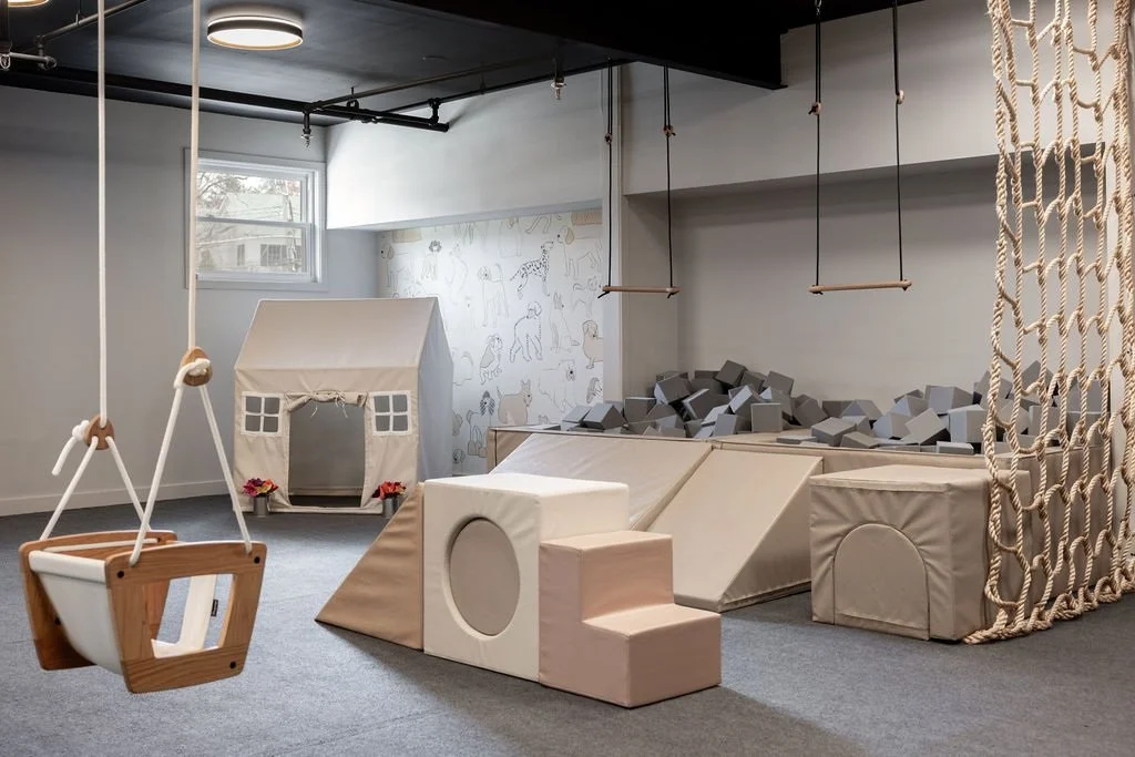 Playroom with a climbing structure, hanging swing and house-shaped play area
