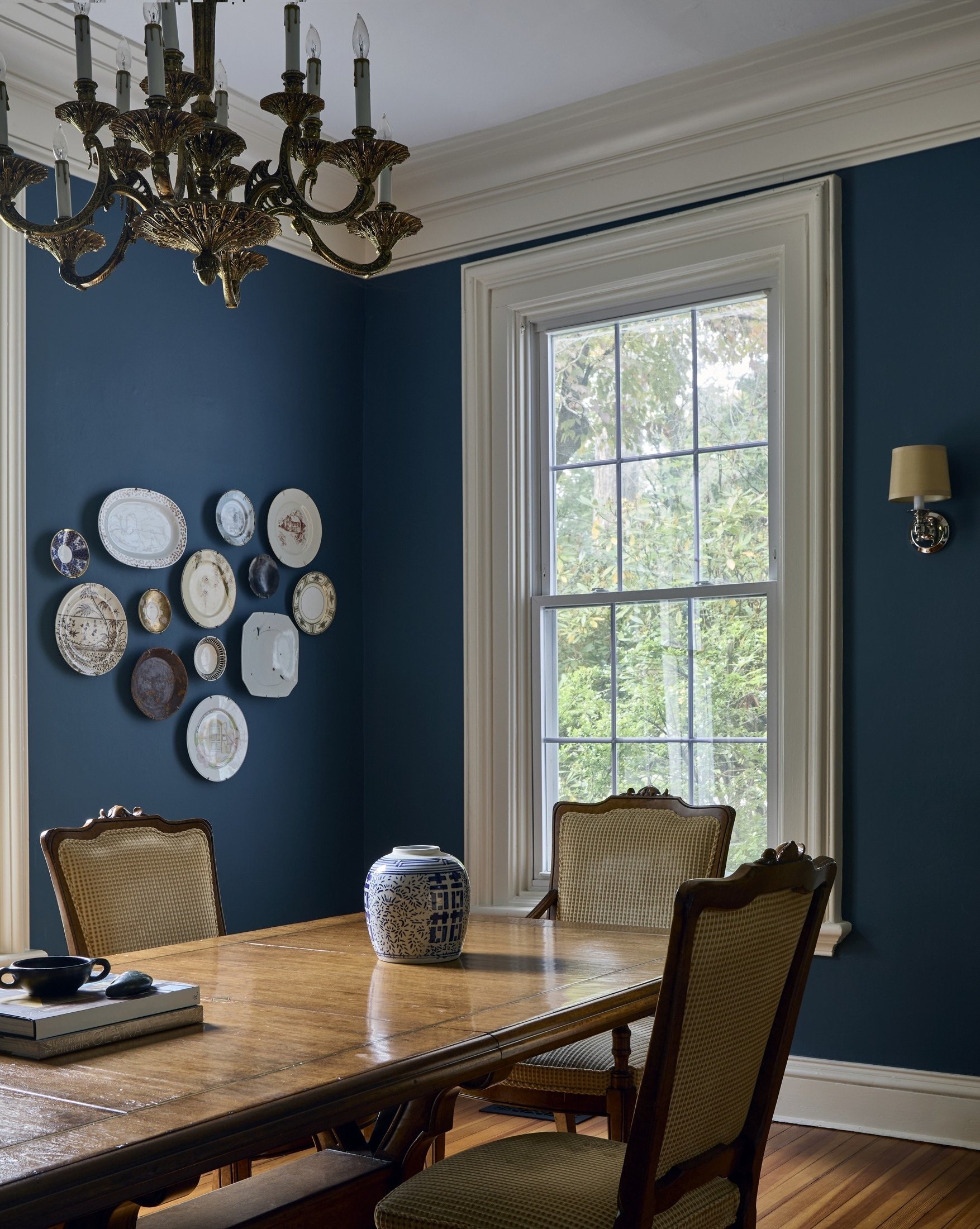 Dining room with blue walls, decorative plates and a chandelier