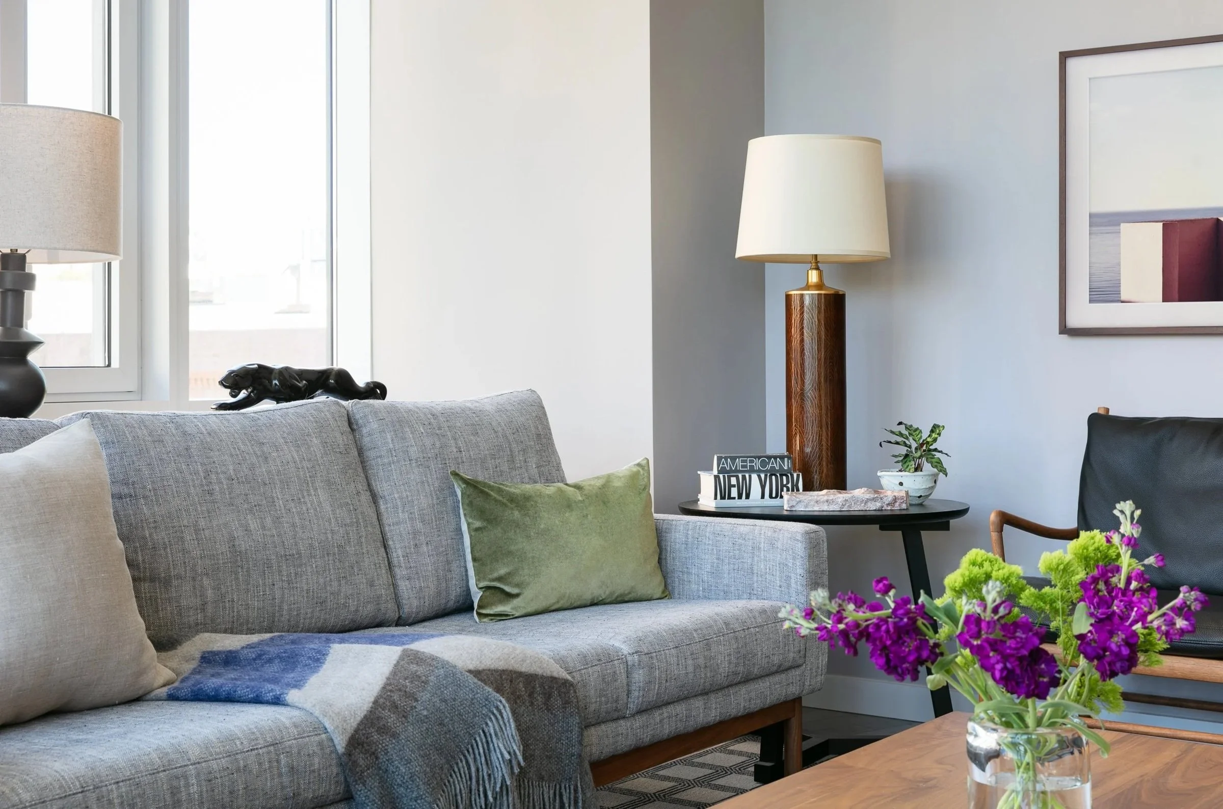 Gray sofa with pillows, a wood side table and flowers
