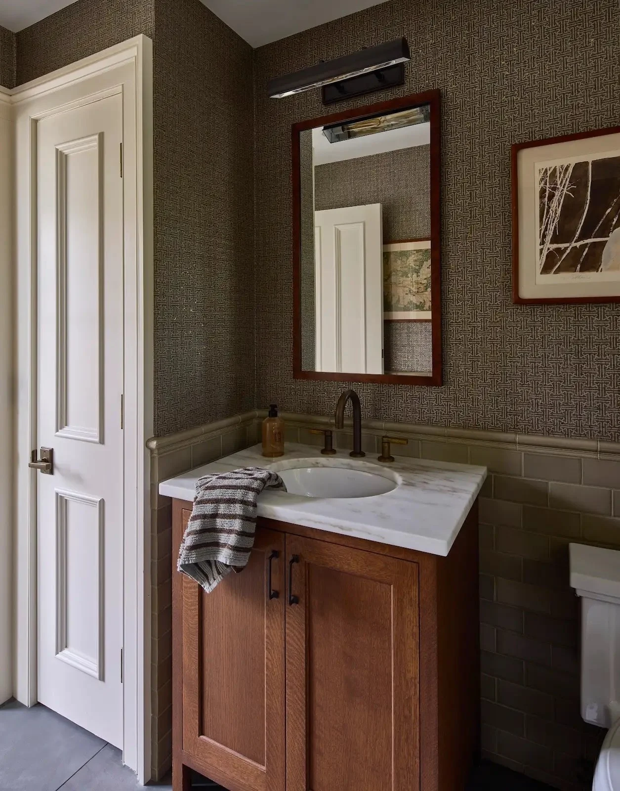 Bathroom with a wood vanity, white fixtures and framed artwork