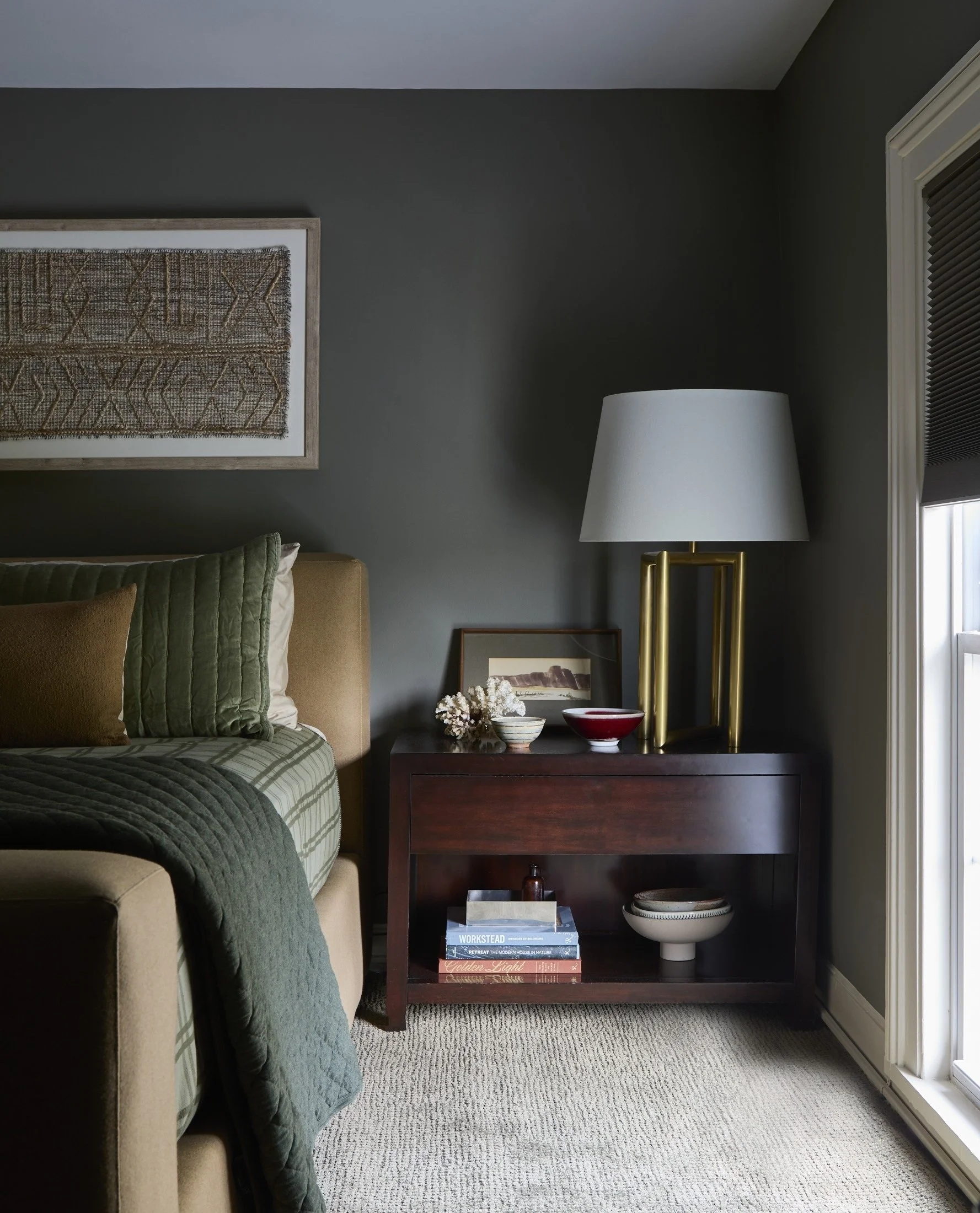 Bedroom with green bedding and a dark wood bedside table