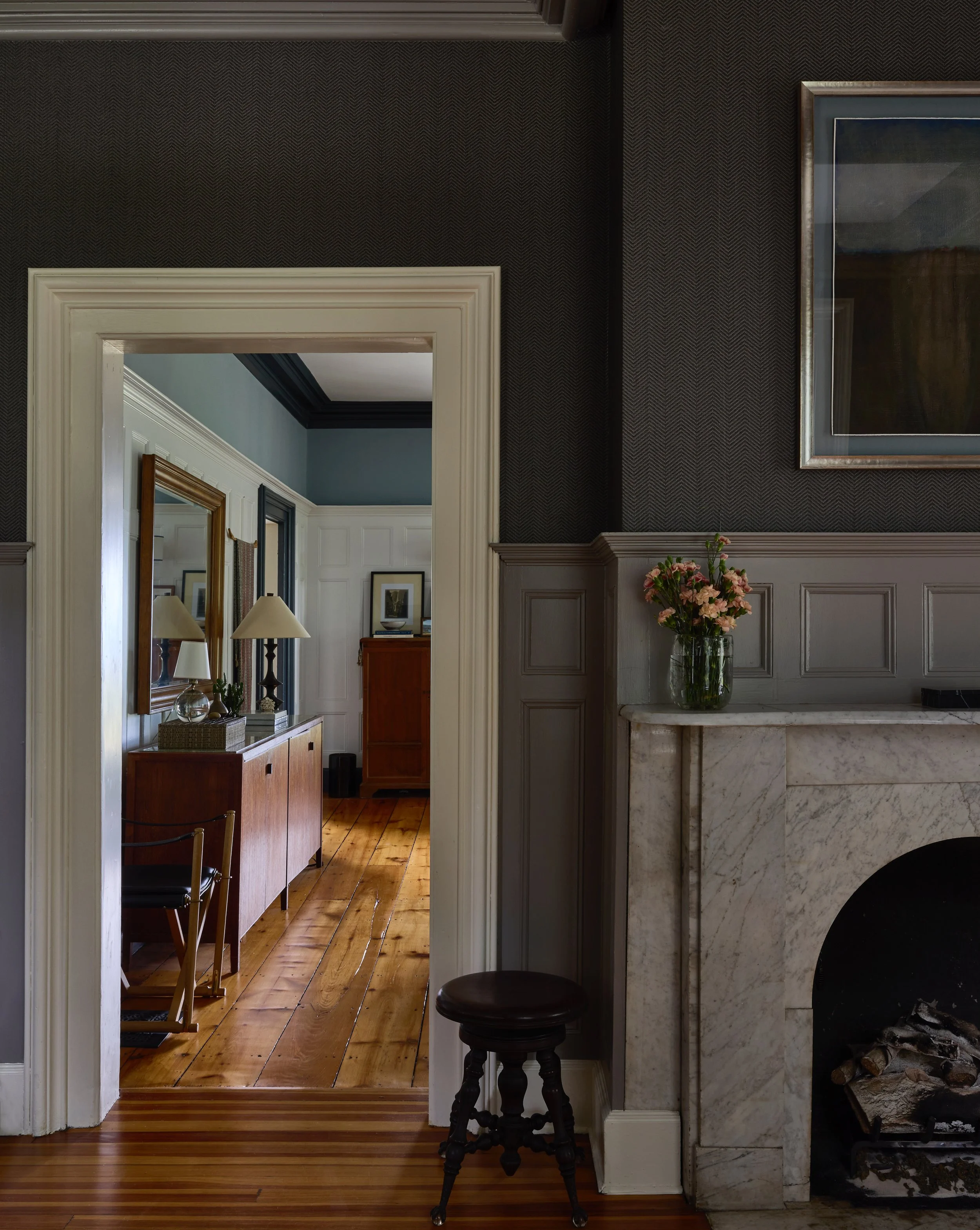 Dark-painted living room looking through to a sunlit room