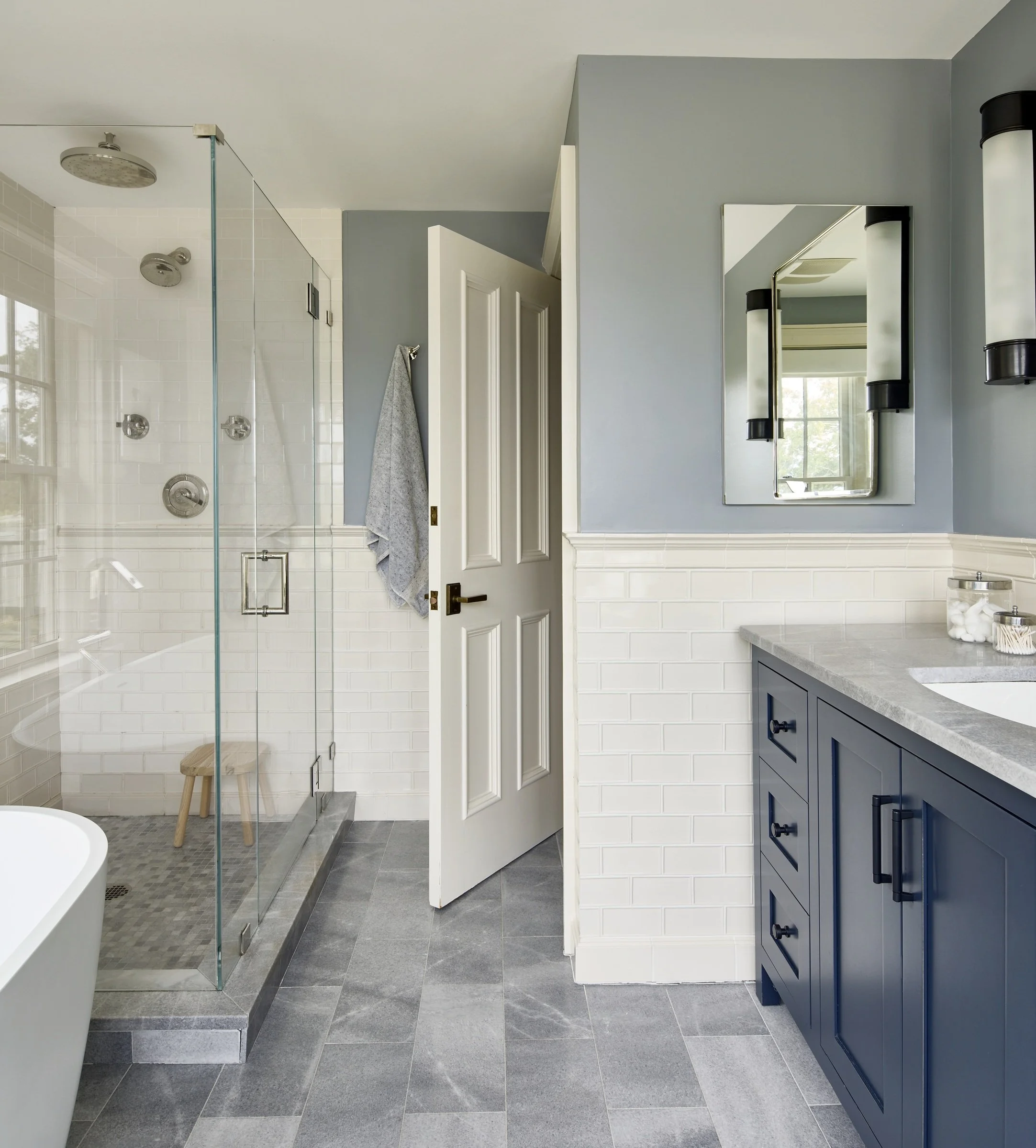 Bathroom with patterned wallpaper, a blue vanity and a glass shower