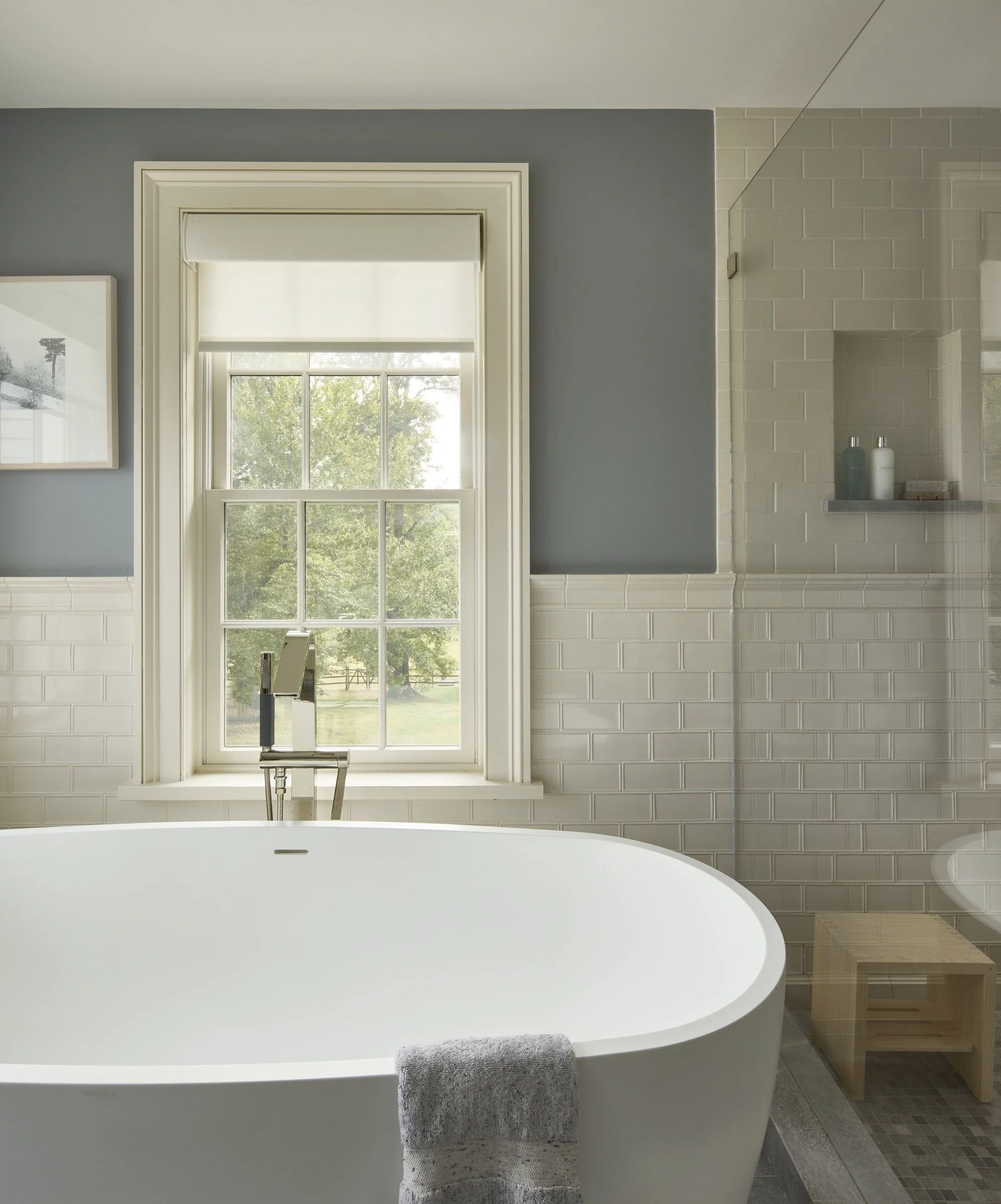 Freestanding bathtub beneath a window in a tiled bathroom