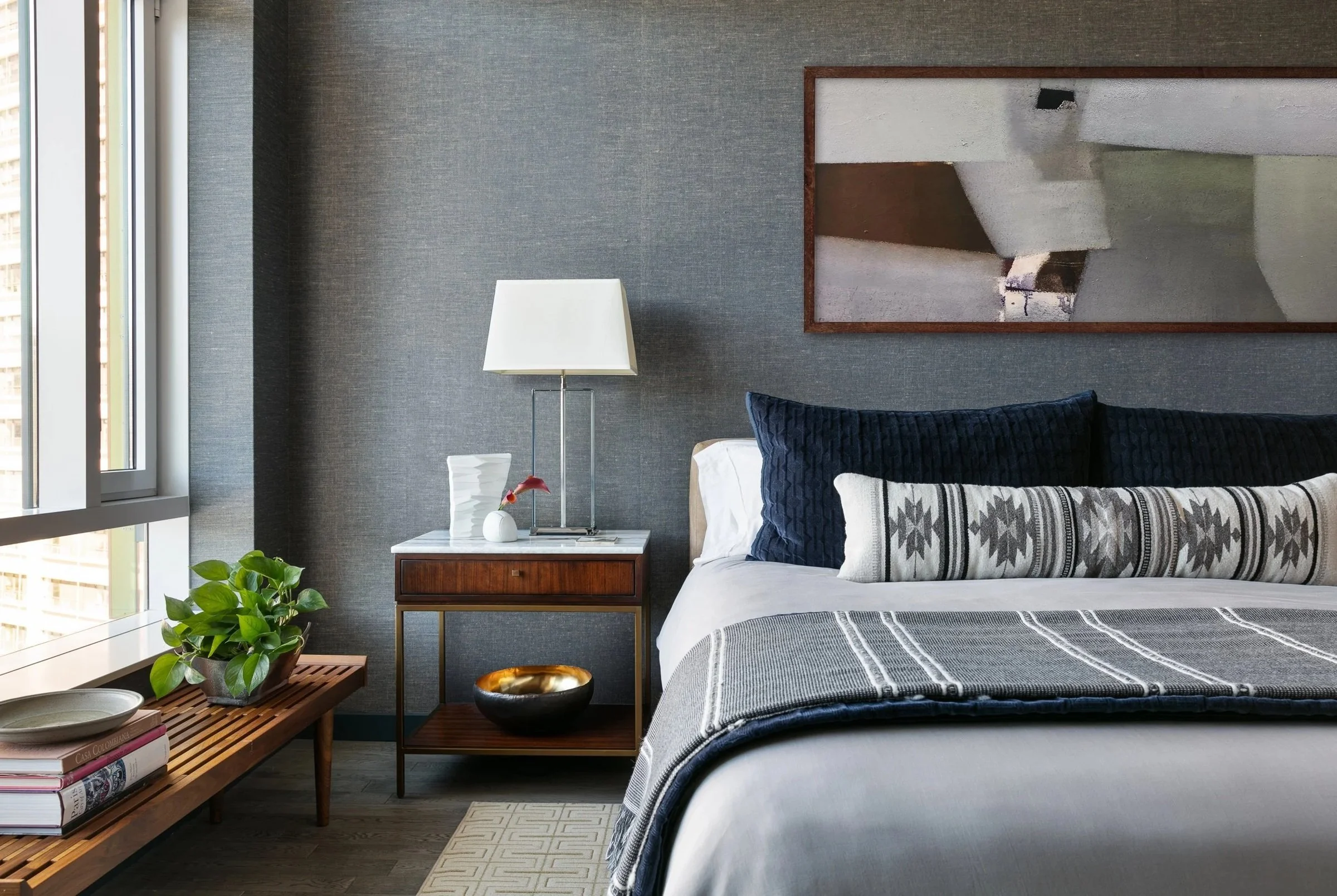 Bedroom with patterned pillows, dark wood bedside tables and wall sconces
