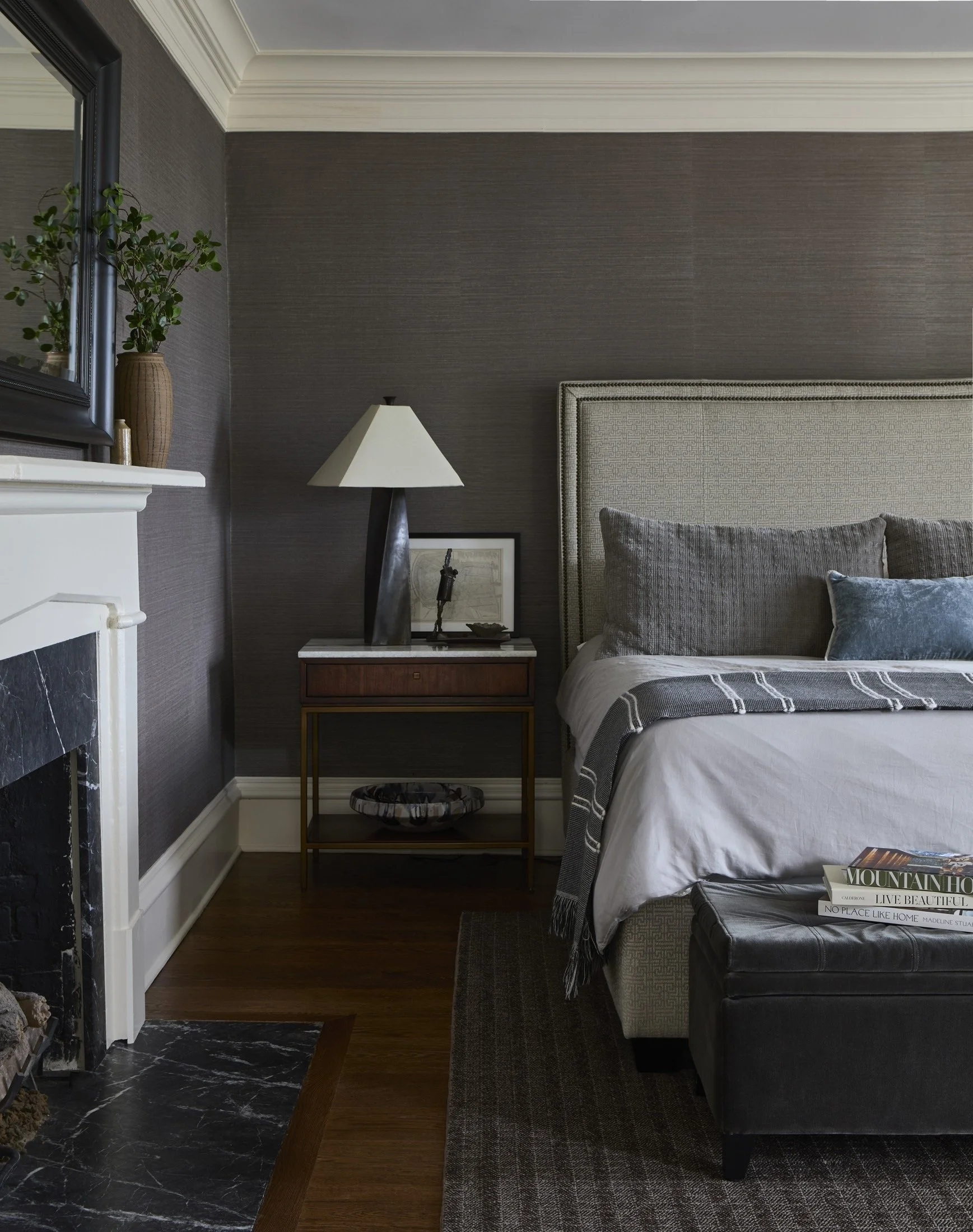 Bedroom with gray bedding, dark walls and a bedside lamp