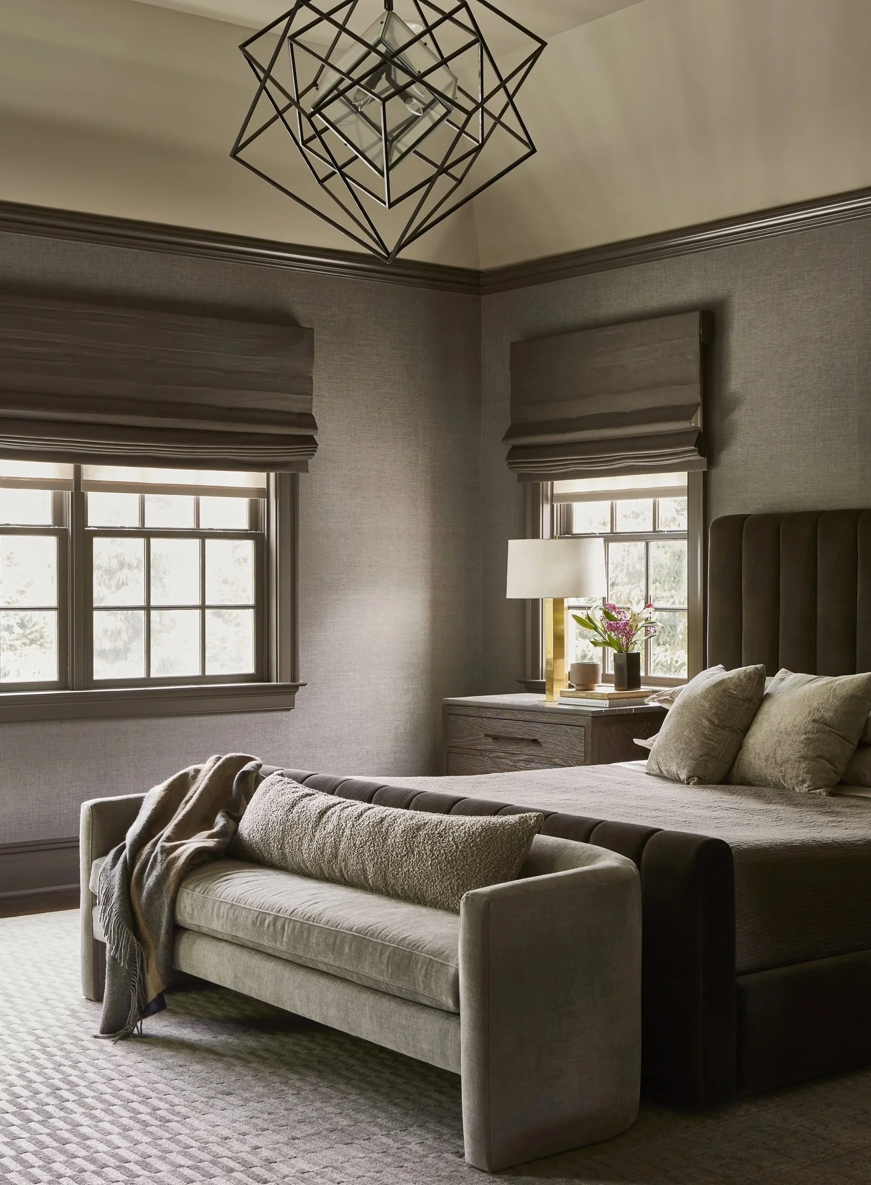 Neutral bedroom with an upholstered chaise and geometric ceiling light