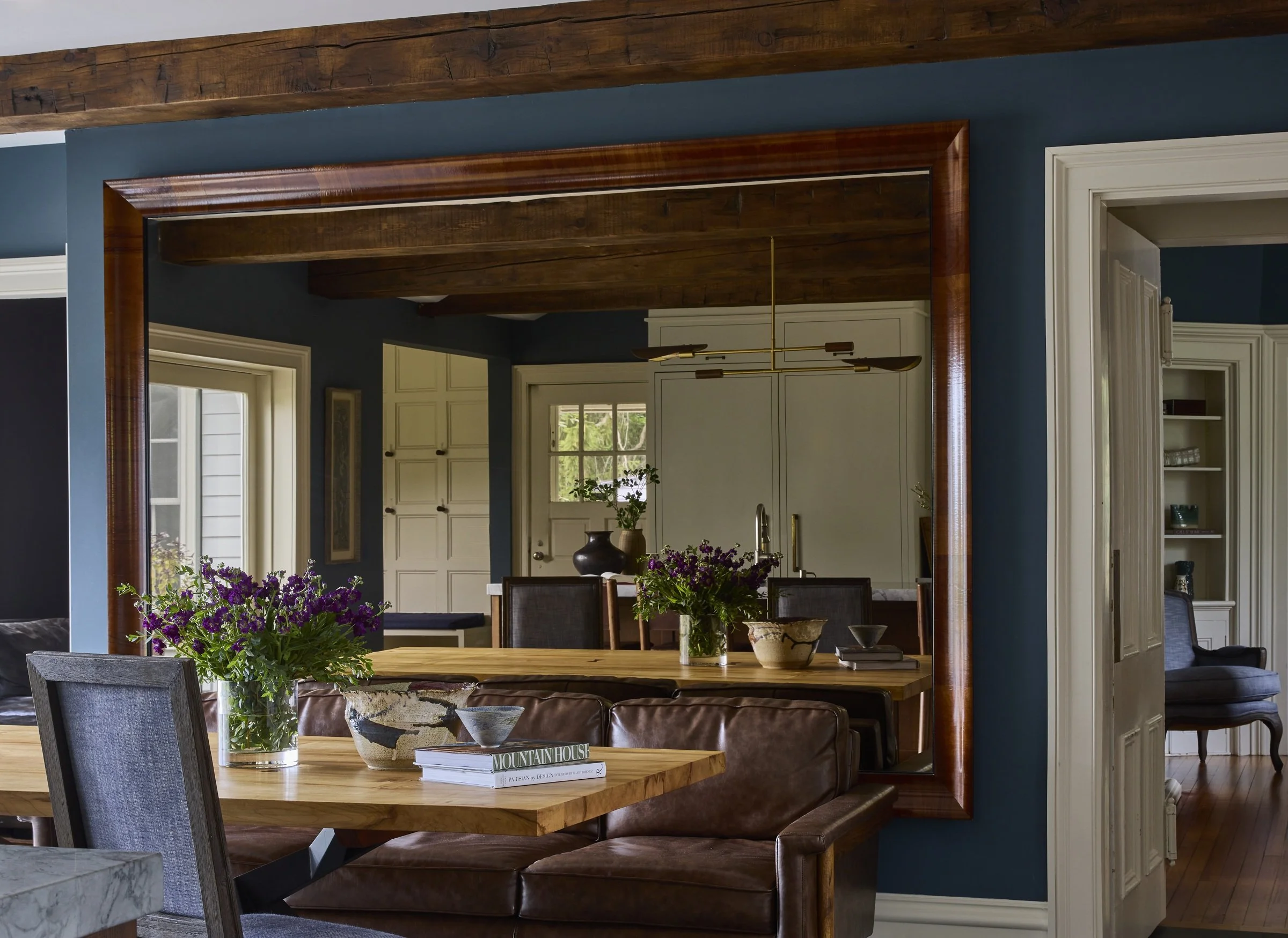 Dining room with blue walls, wood beams and a large framed mirror