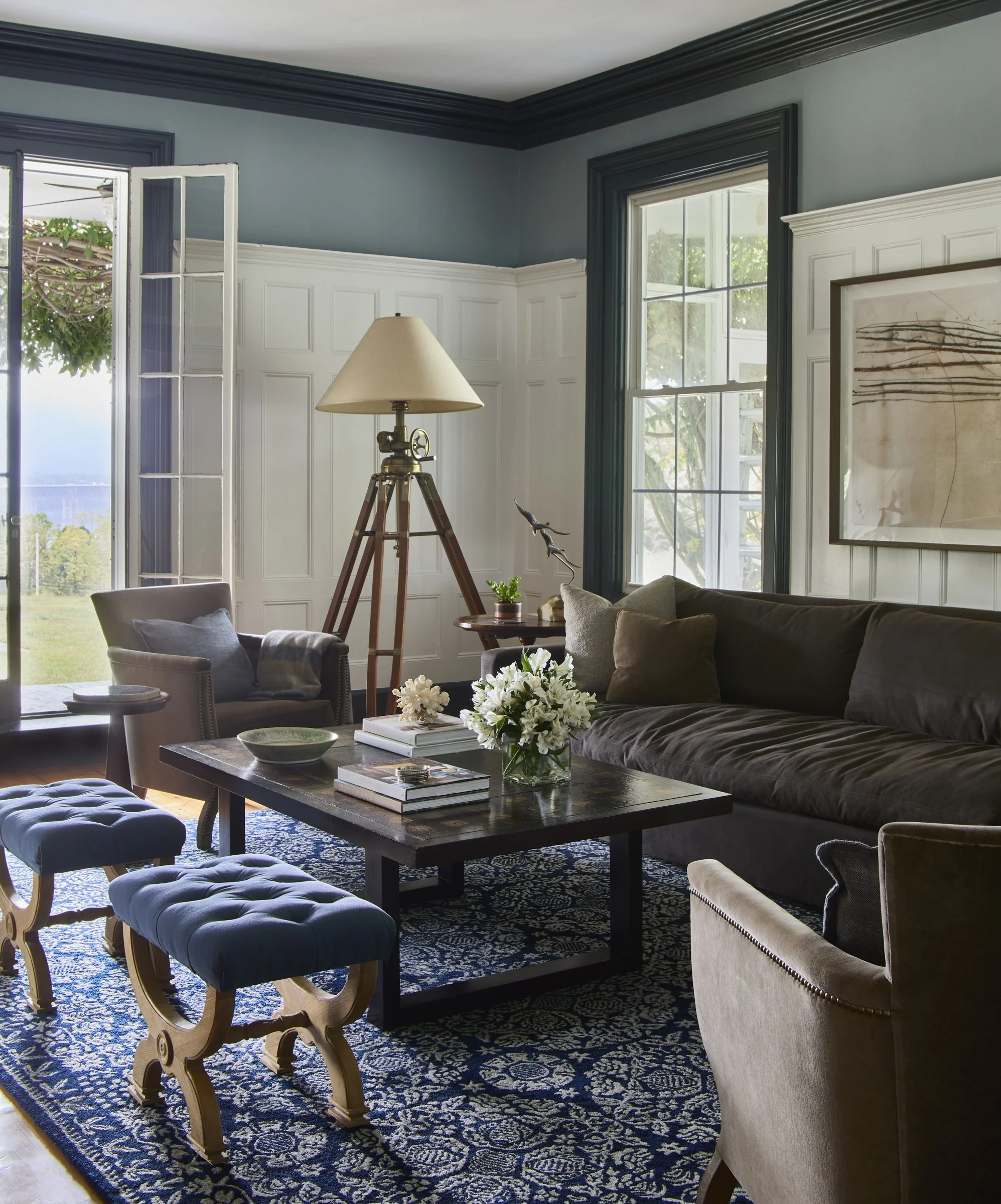 Living room with dark trim, a gray sofa and large windows