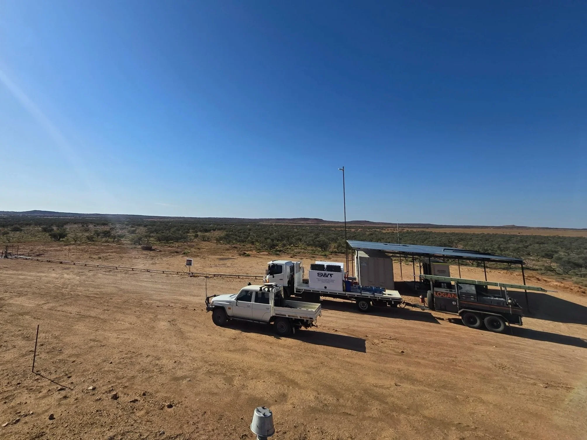 A desert landscape with hardware and vehicles, including trucks and equipment, under a clear blue sky.