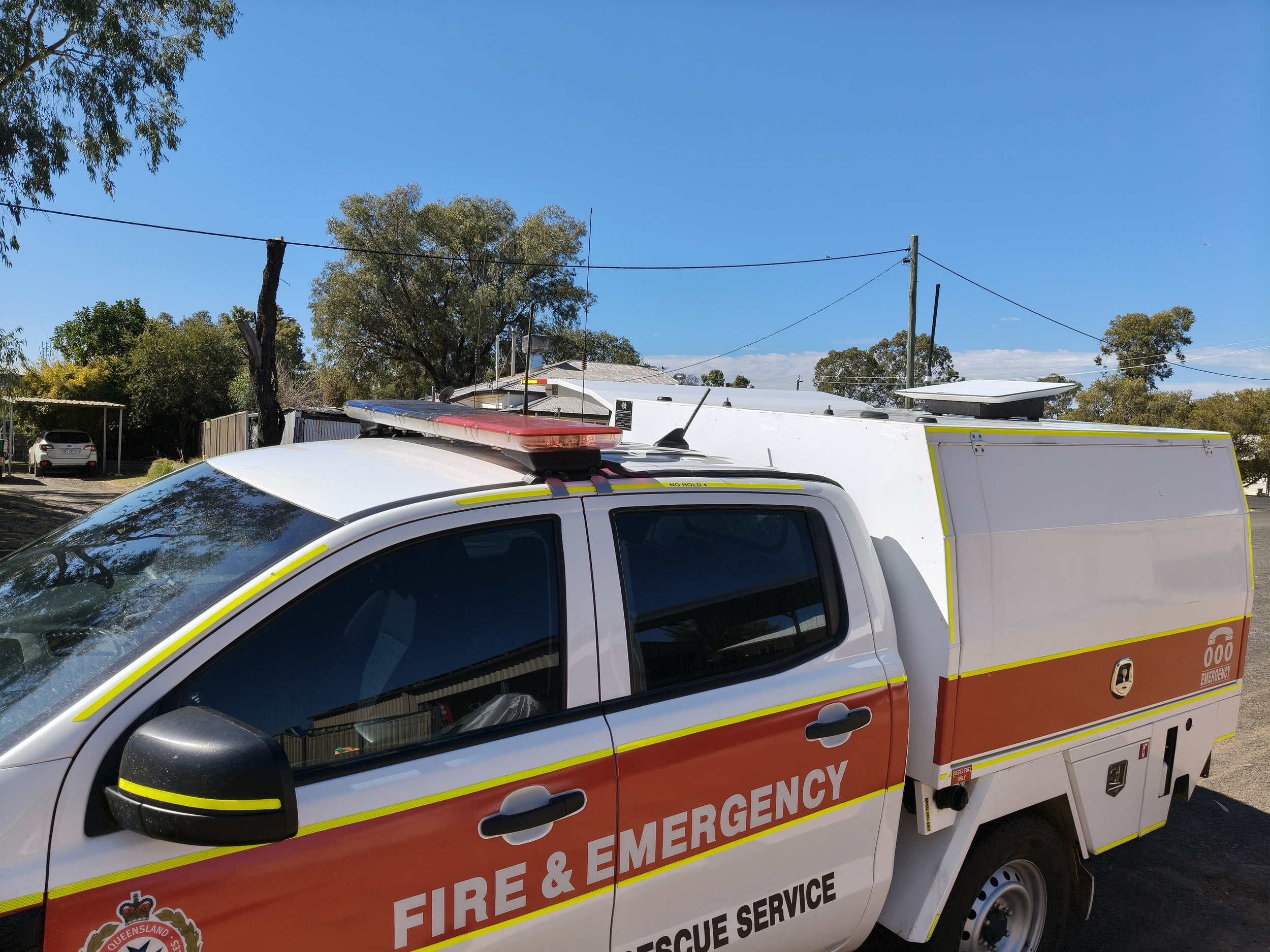 Emergency fire rescue vehicle parked outdoors, with trees and a blue sky in the background.