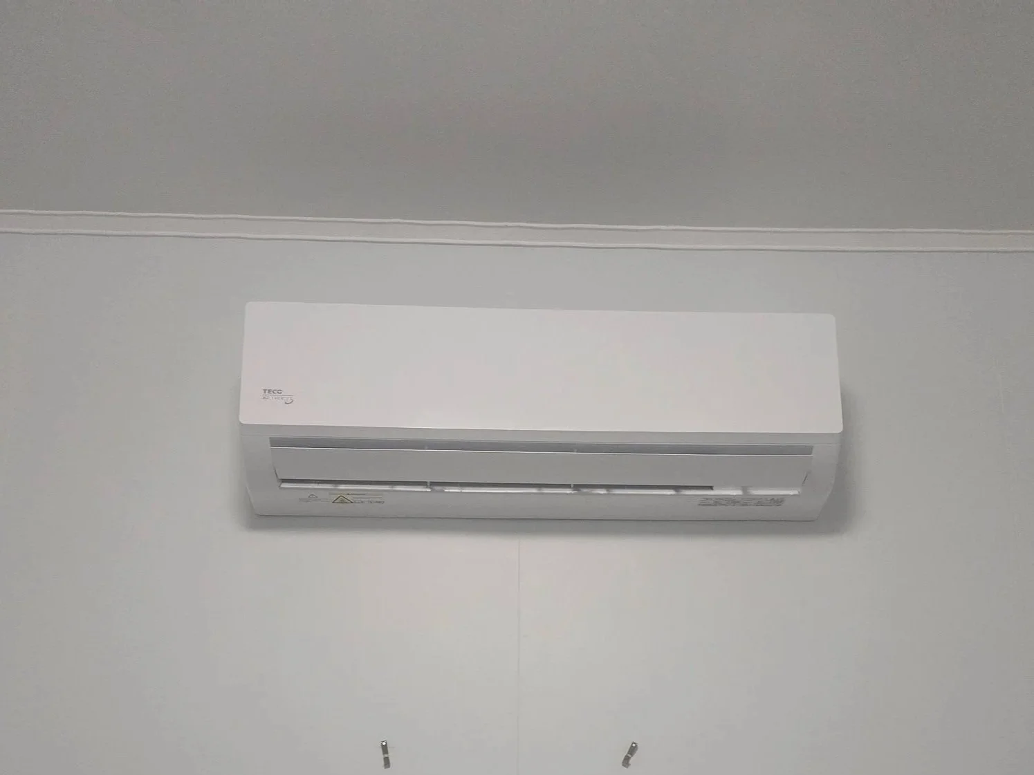 Wall-mounted white air conditioner unit installed on a plain white wall.