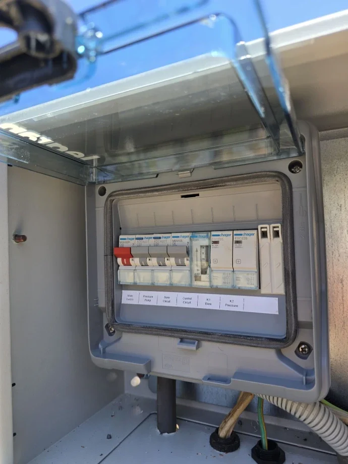 Electrical circuit breaker panel with multiple switches in a gray enclosure.