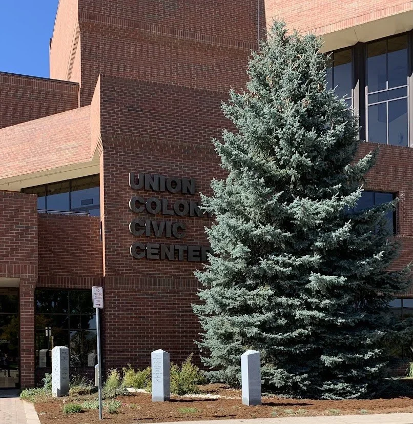 Exterior view of the Union Colton Civic Center with a large evergreen tree in front of a brick building.
