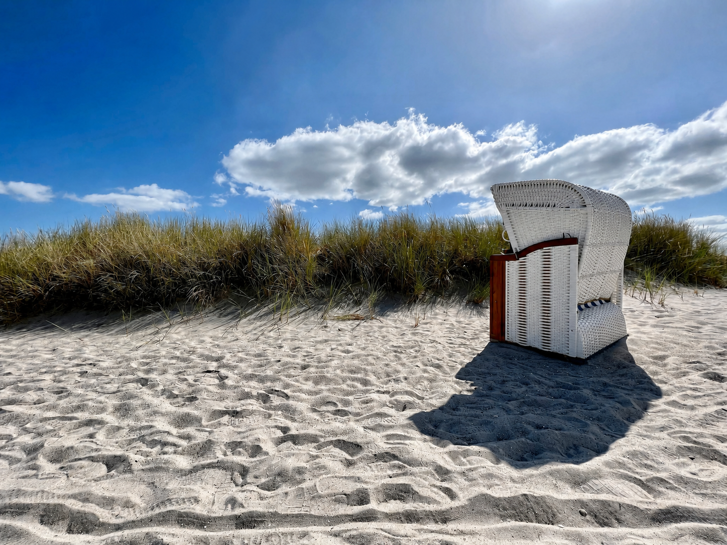Strandkorb am Ostseestrand bei Grömitz mit Dünen, Sand und blauem Himmel