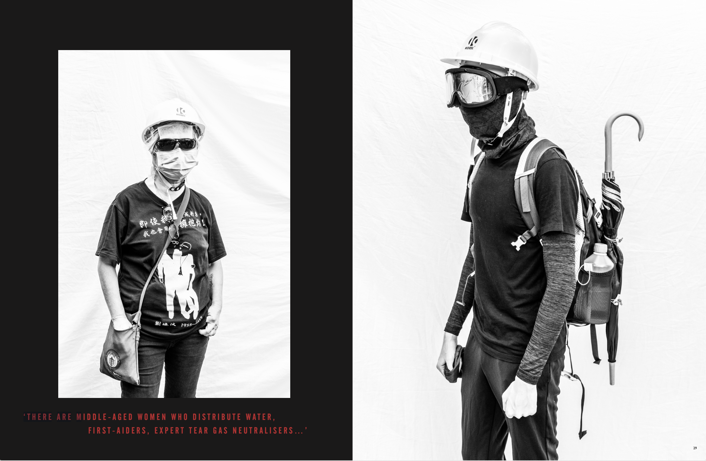 Black and white photo of two middle-aged women wearing safety helmets, goggles, and face masks. One woman is standing with her hands in her pockets, wearing sunglasses and a graphic t-shirt. The other woman is in profile, carrying a backpack with an 