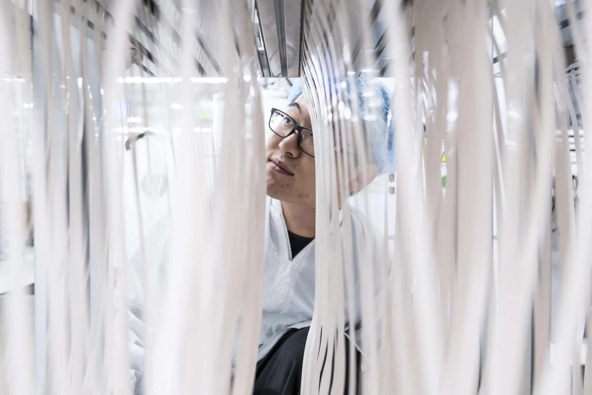 Person inspecting or working on paper or plastic materials in an industrial or manufacturing setting.