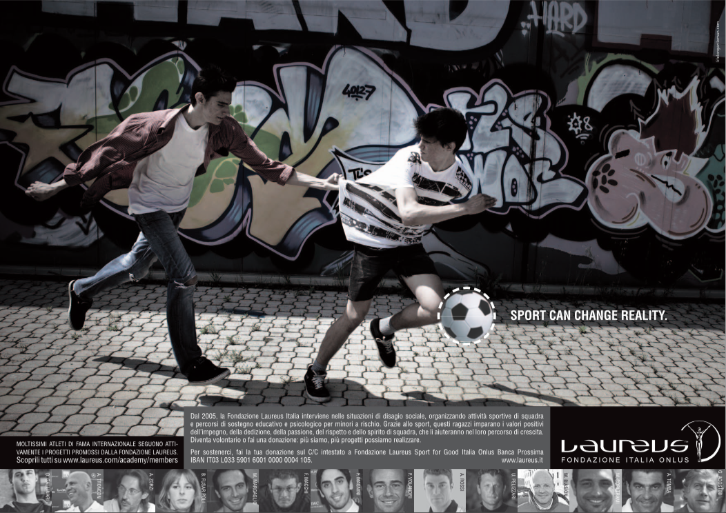 Two young men playing soccer against a graffiti-covered wall, with one pulling the other by a shirt, as the soccer ball moves past them. The image includes a caption about sports changing reality.