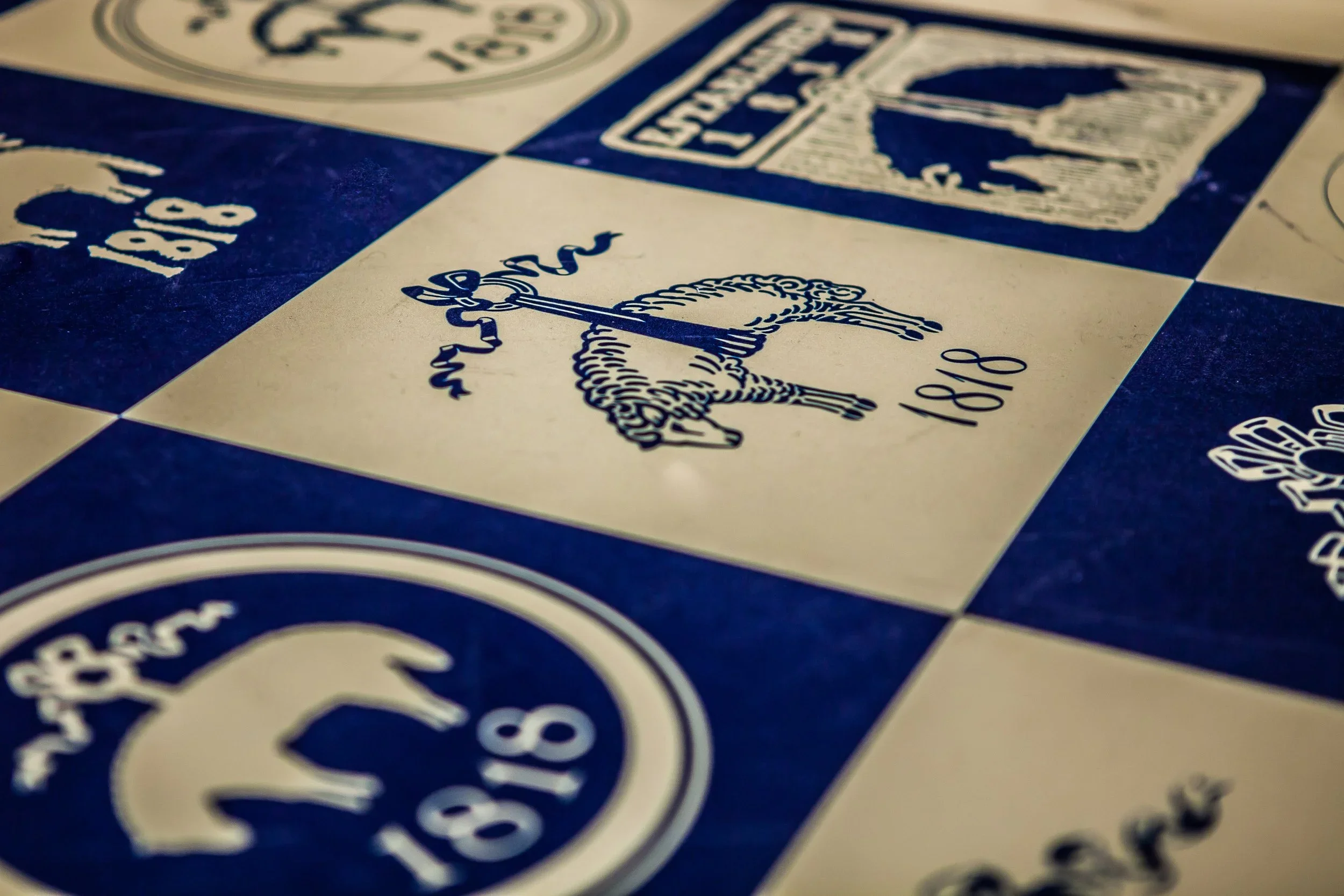 Close-up photograph of a board game with blue and white squares. One square features an illustration of a knight on horseback holding a sword. Other squares contain text and symbols.