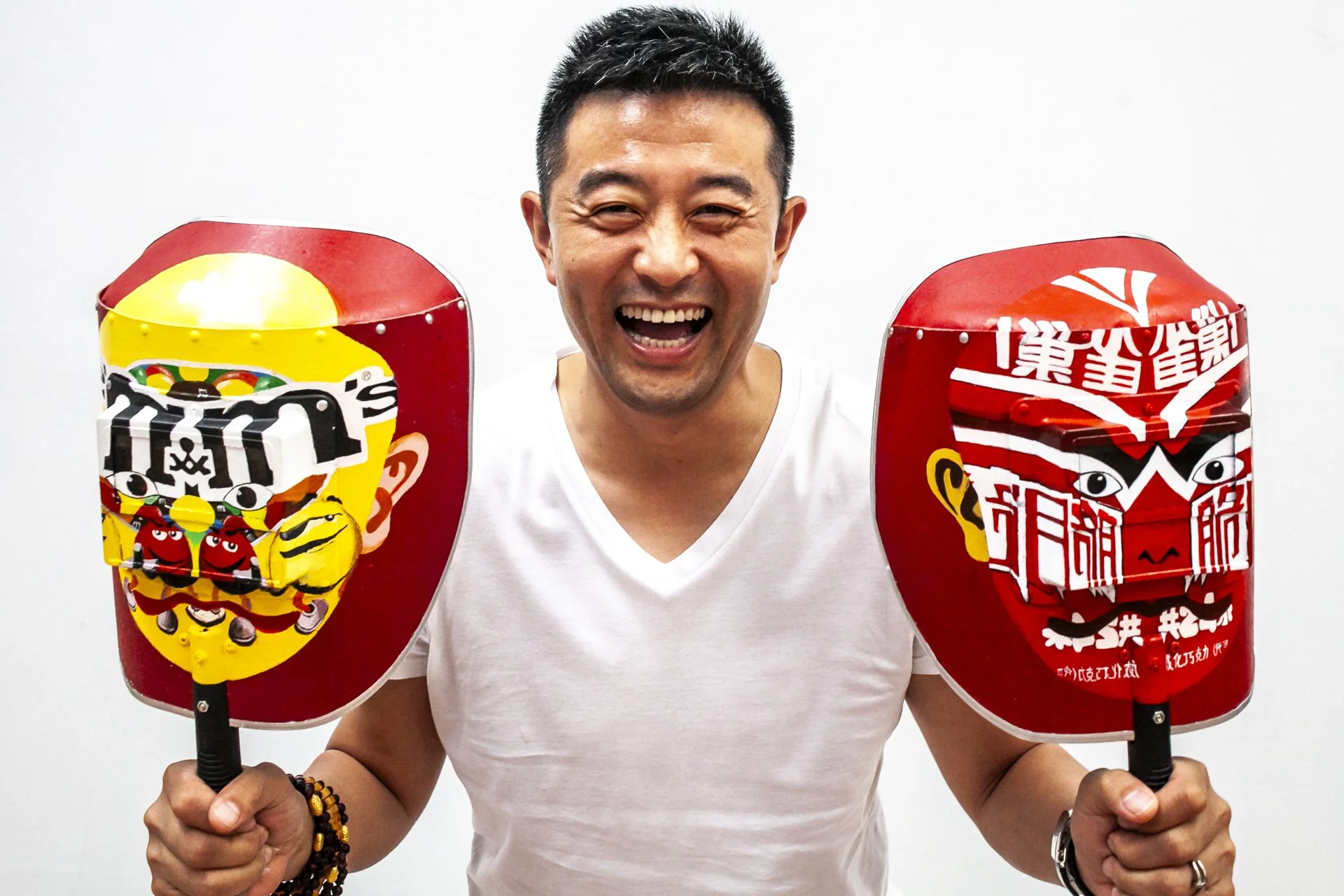 A smiling man holding two colorful Chinese lanterns with cartoon characters and Chinese writing, against a plain white background.