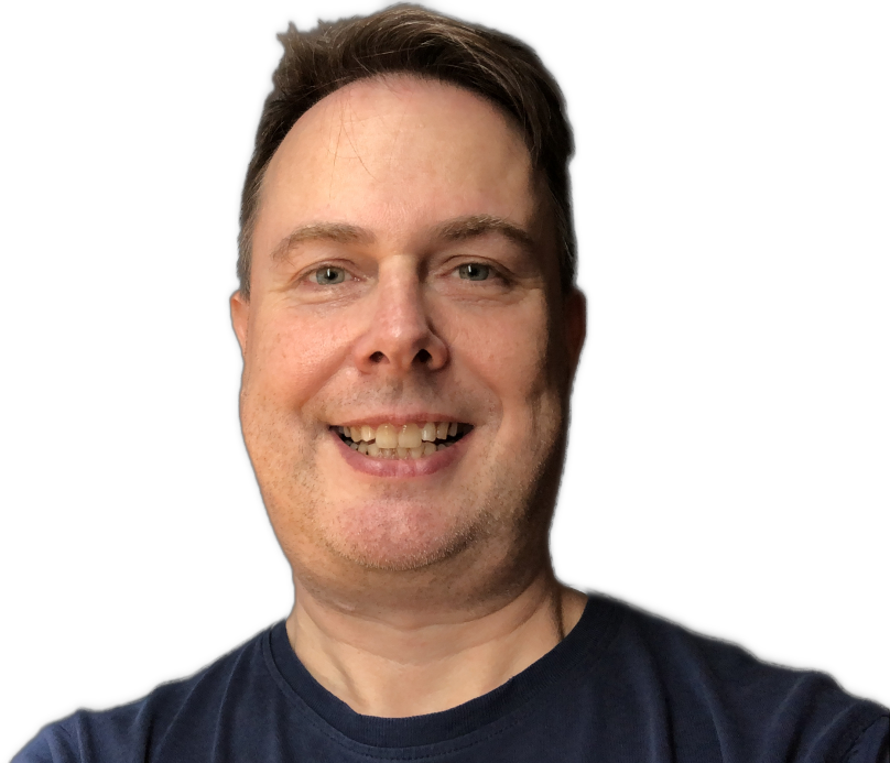 Lächelnder Mann mit kurzen braunen Haaren vor schwarzem Hintergrund, trägt ein dunkles T-Shirt.