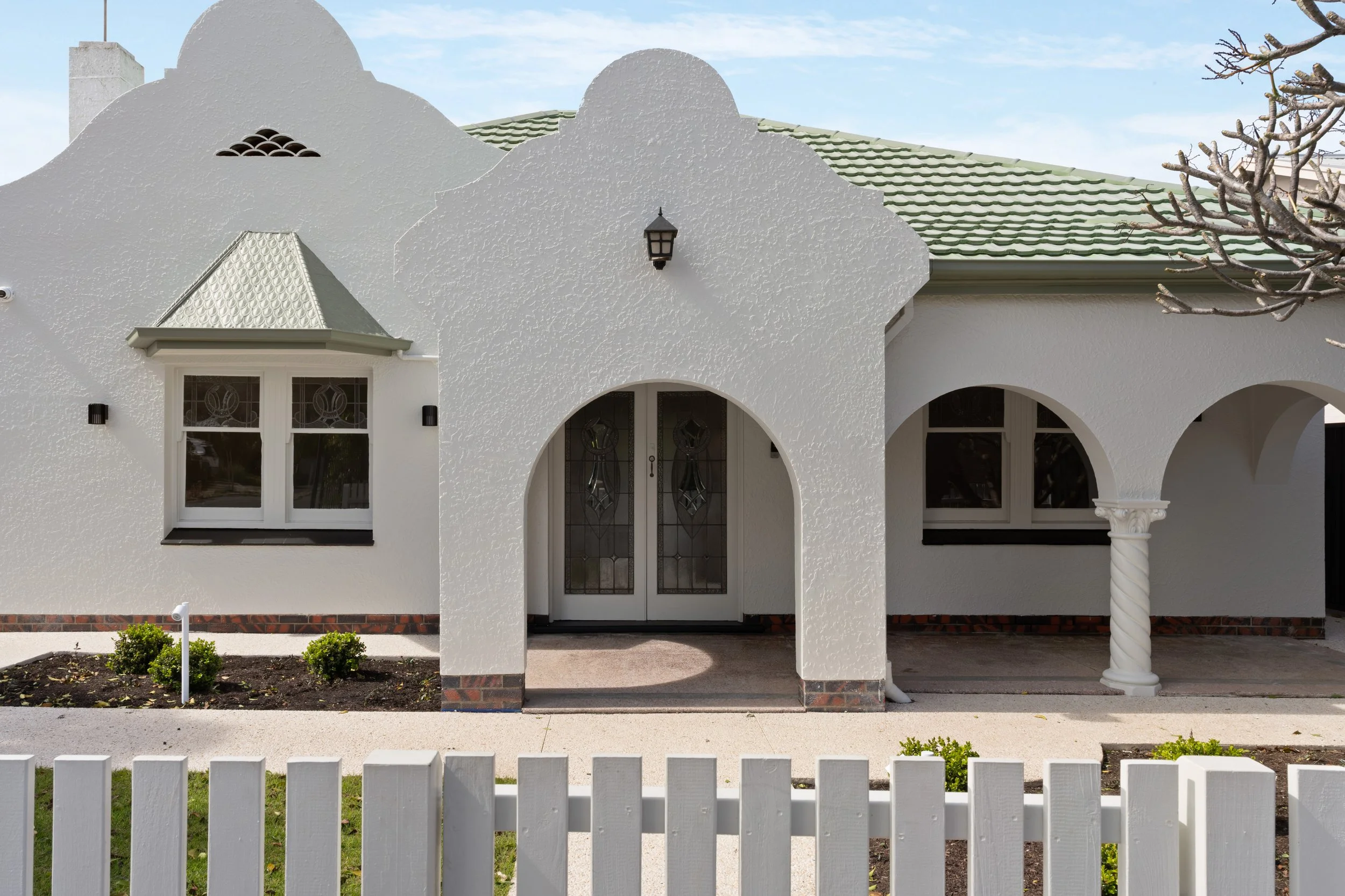 Curved Art Deco entrance façade beneath a green tiled roof in Glenelg North