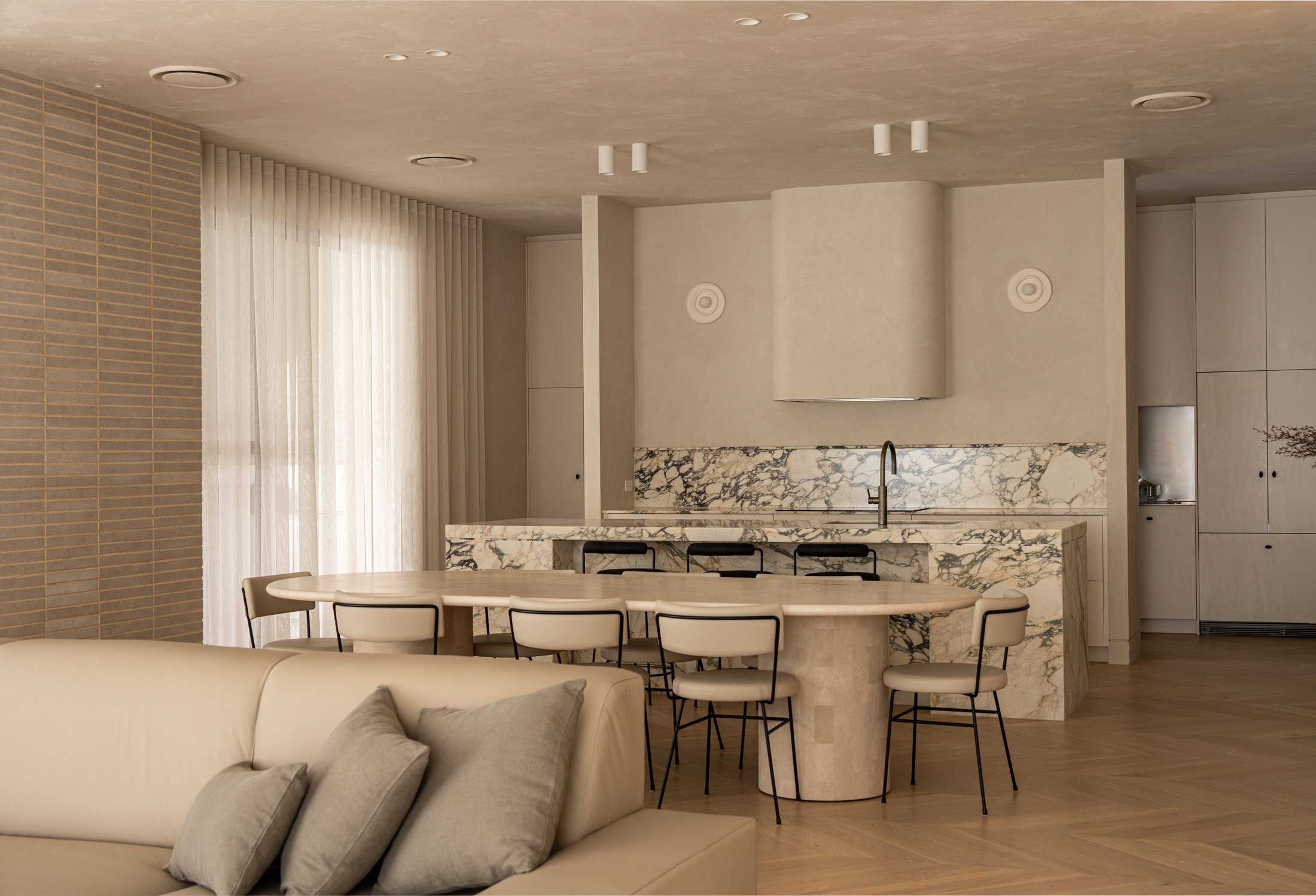 St Morris kitchen with textured plaster surfaces, a sculptural rangehood and veined stone splashback