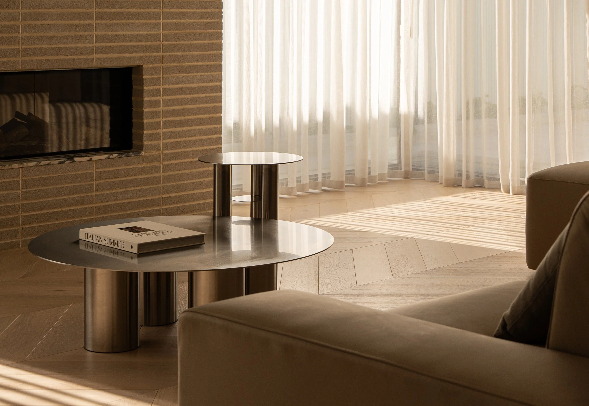 Metal side tables and pale seating beside sheer curtains in St Morris