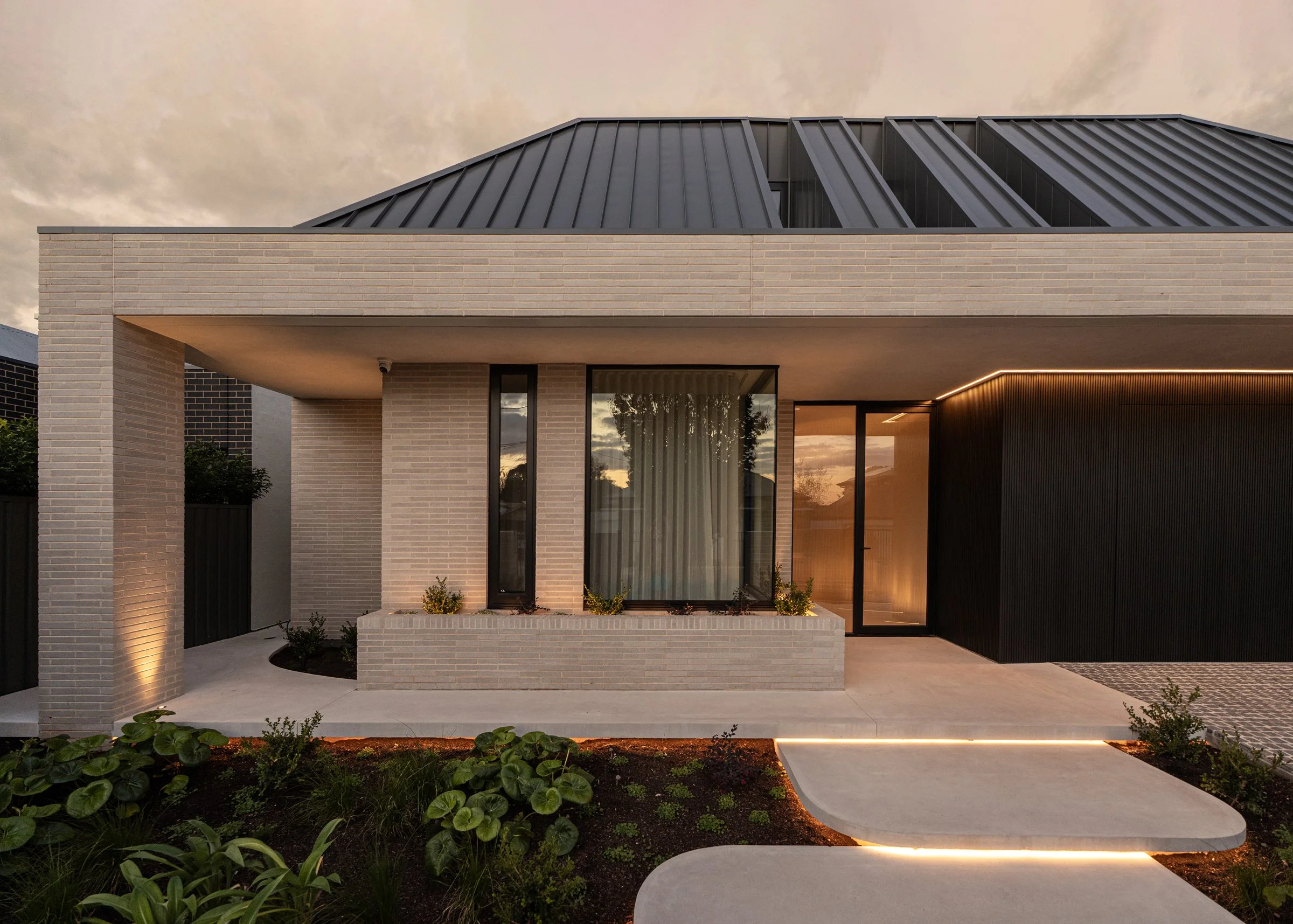 St Morris home façade with dark roof cladding and illuminated landscaping