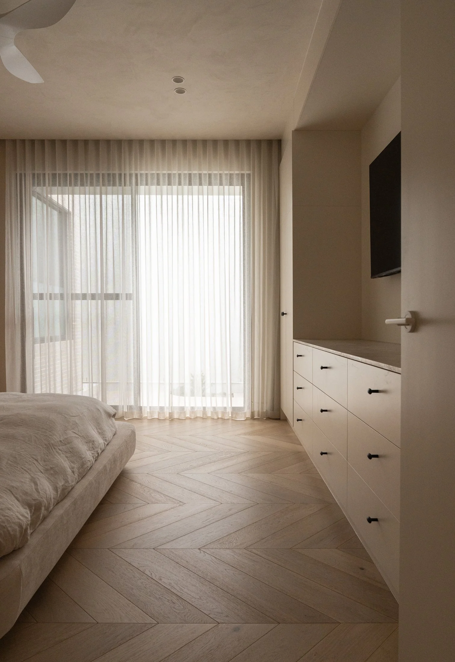 St Morris bedroom with sheer curtains and fitted pale cabinetry