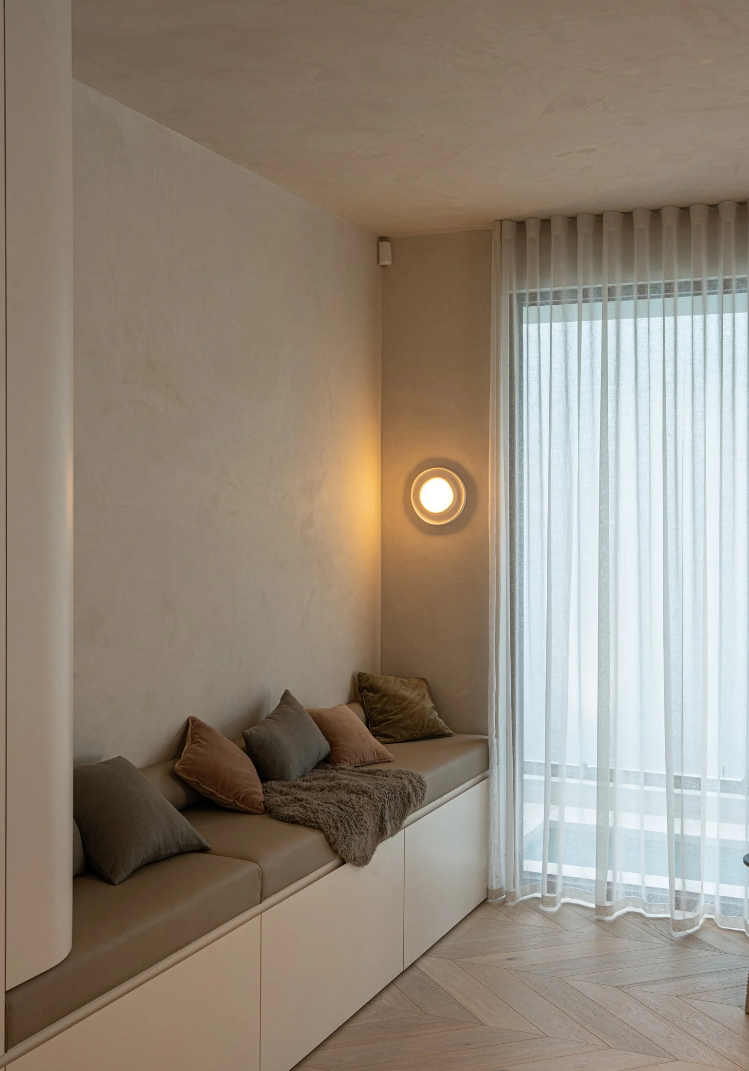 Built-in window seat beside sheer curtains in the St Morris living room