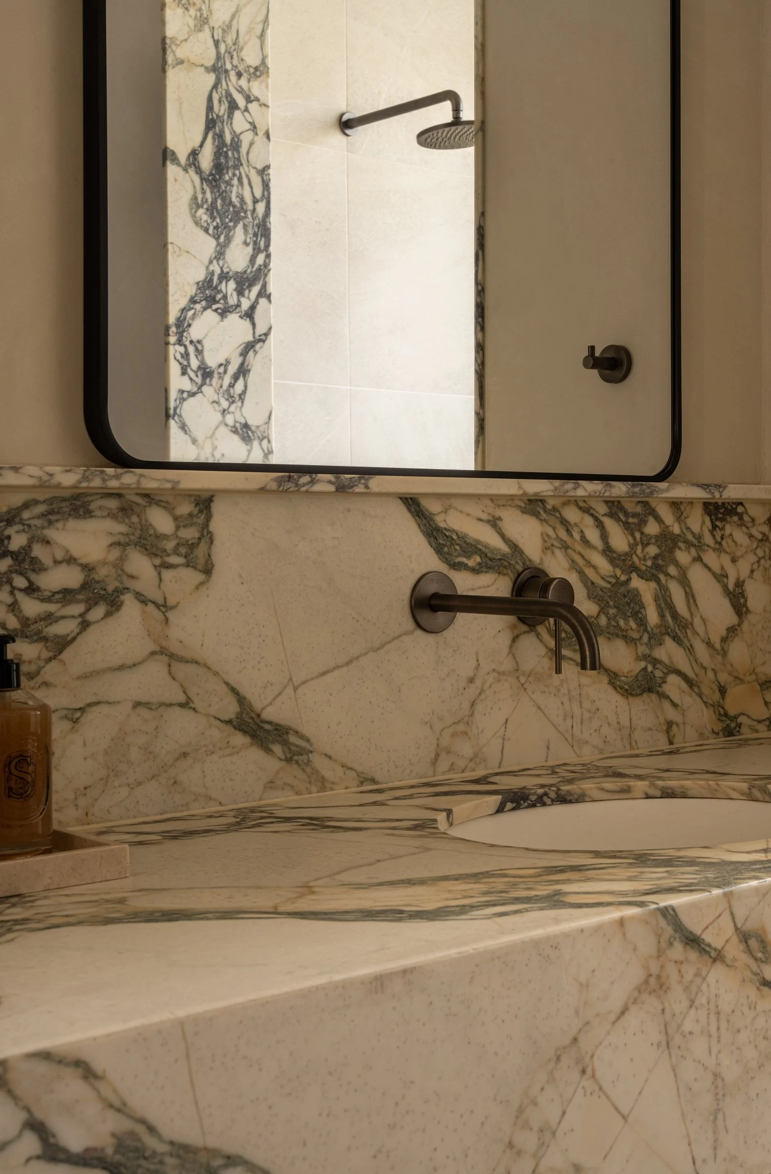 Close-up of the veined stone basin and mirrored bathroom cabinet in St Morris
