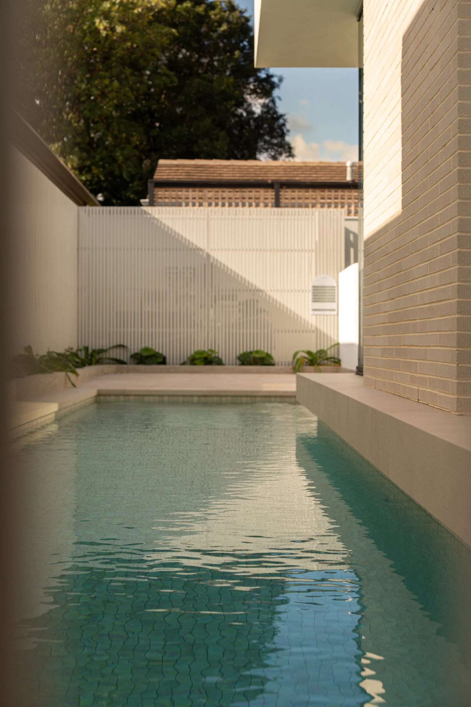Swimming pool bordered by pale brickwork and a white boundary wall in St Morris