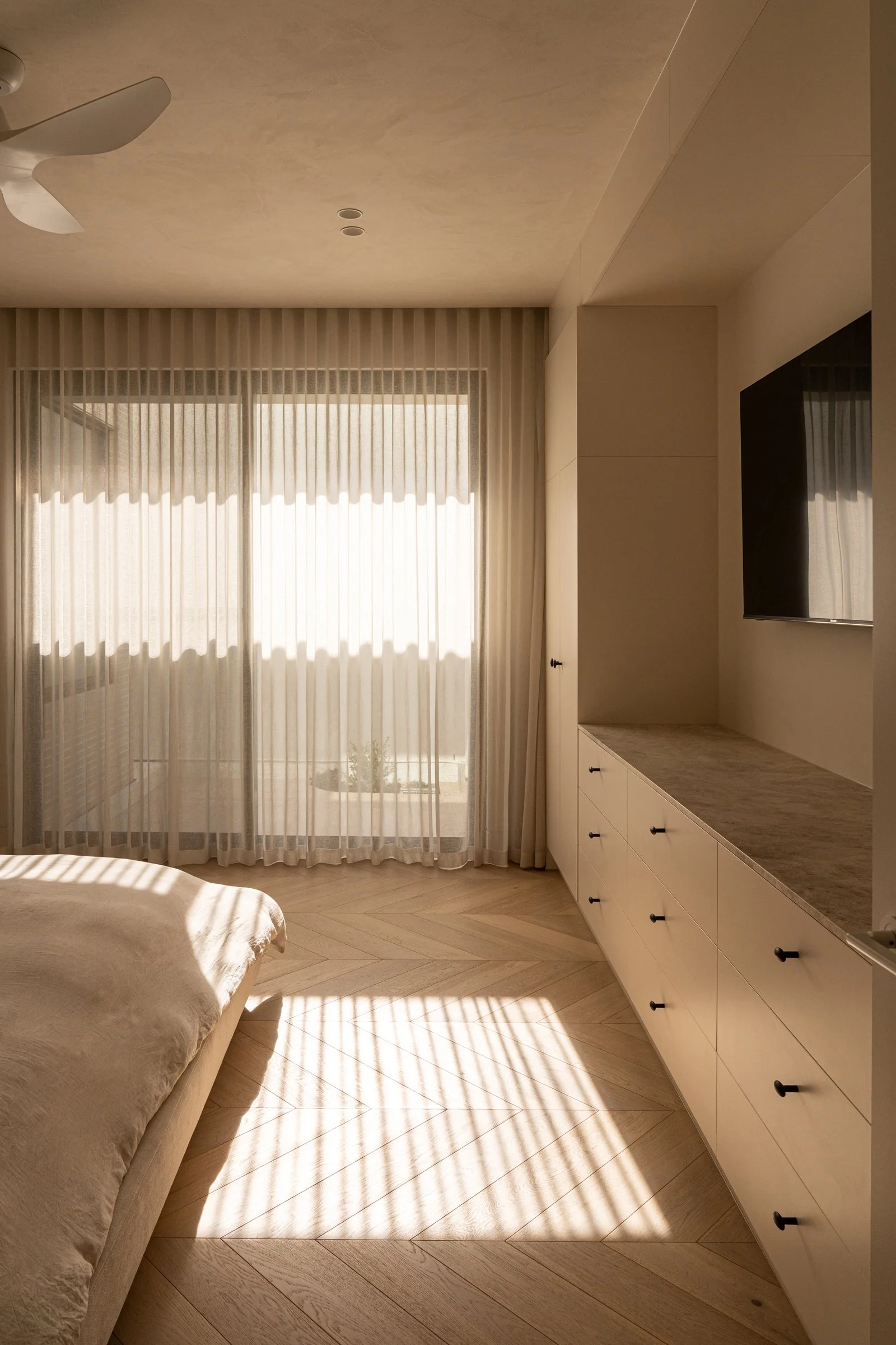 Sunlight through sheer curtains onto the timber bedroom floor in St Morris