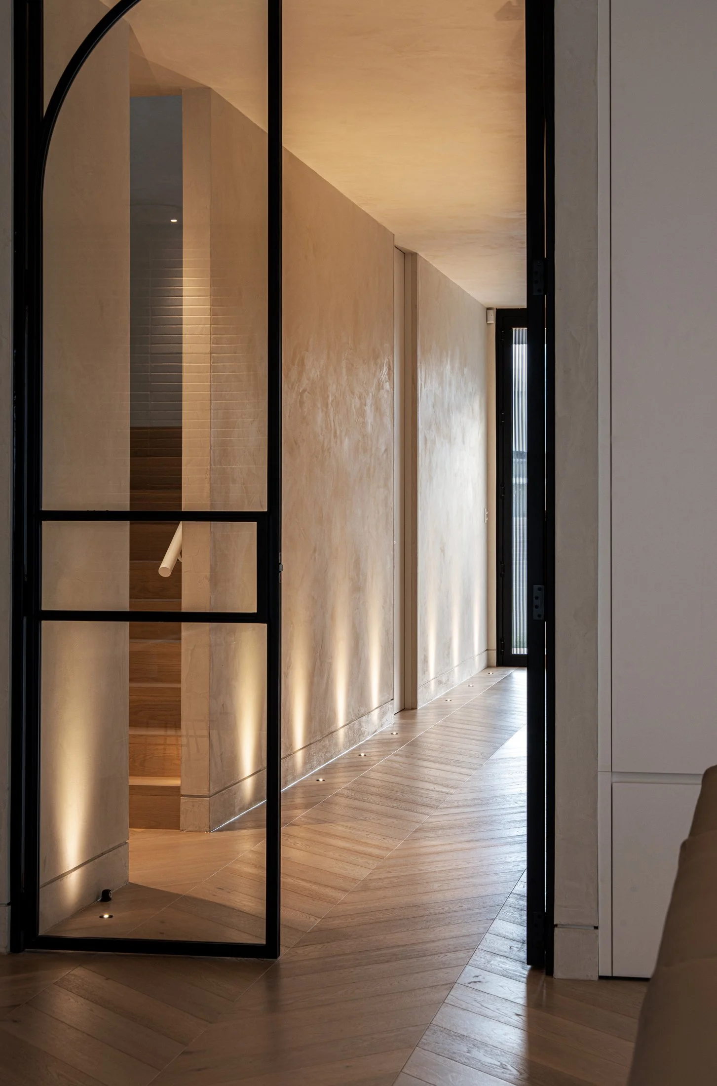St Morris entry corridor with textured plaster walls and dark-framed glazing