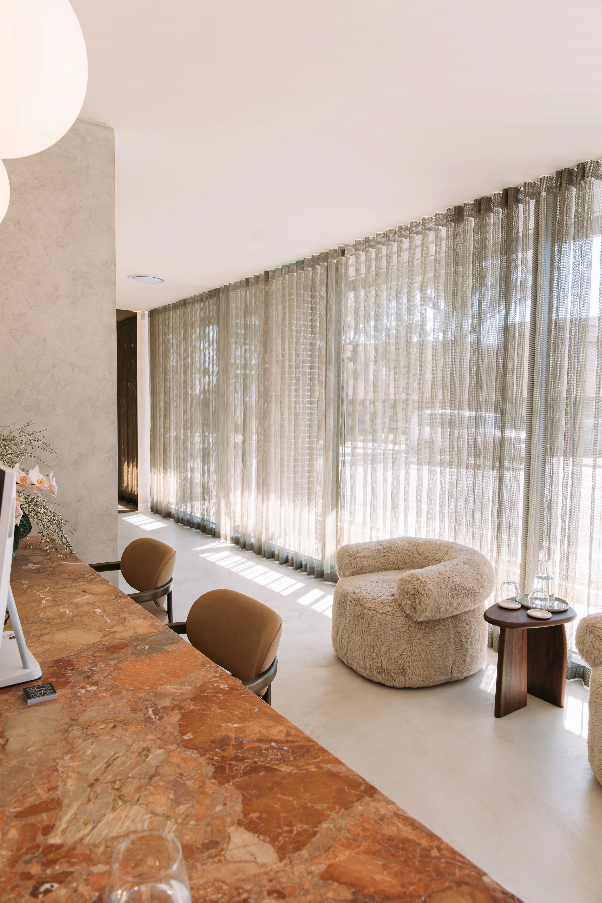 Seating and low tables beside the curtained window at Elixir Skin Fitness