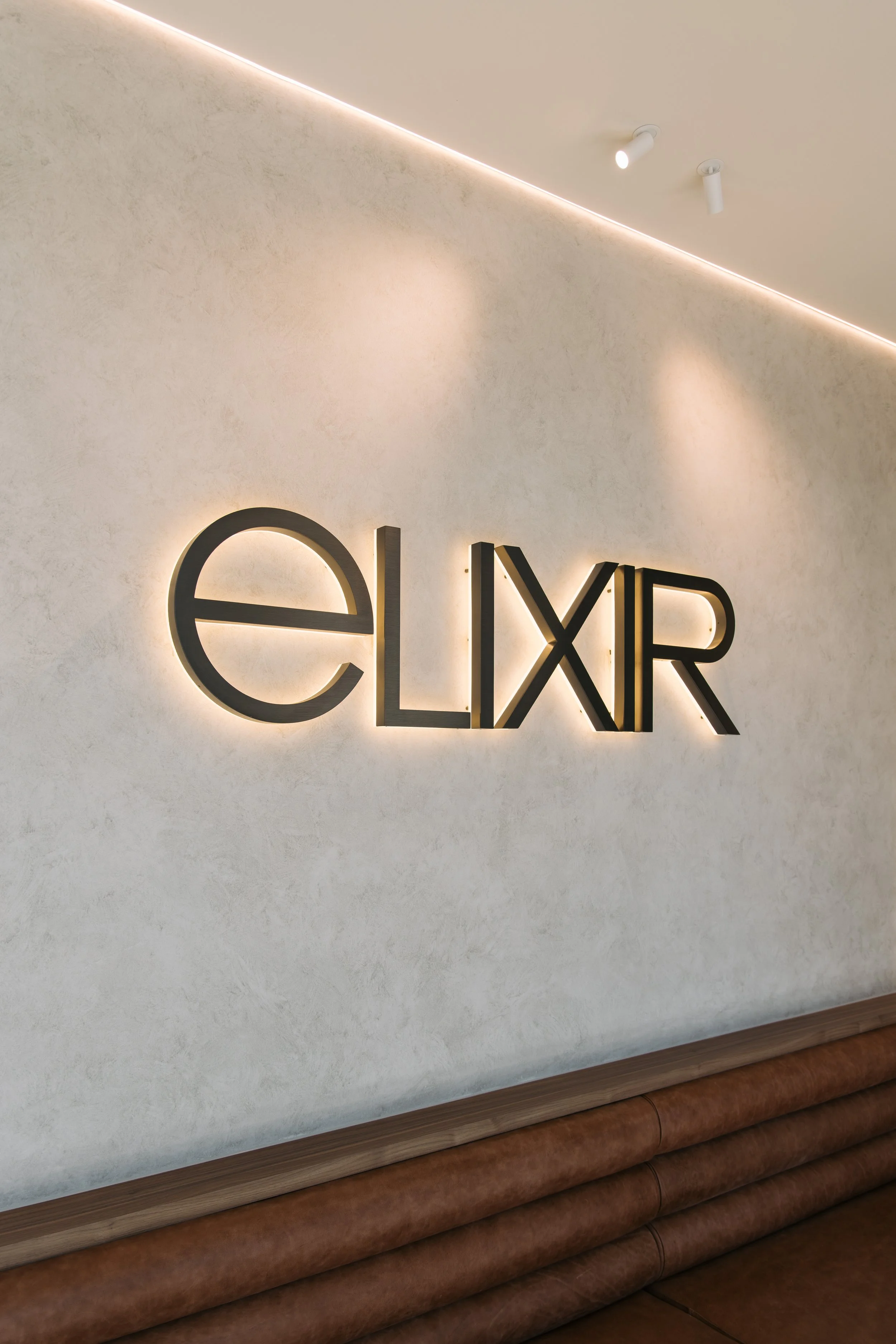 Elixir logo on a textured reception wall at Elixir Skin Fitness in Norwood