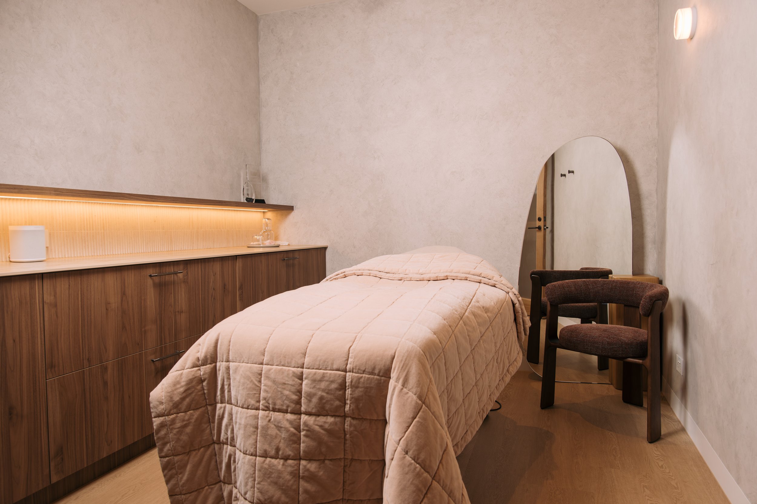 Treatment bed with textured linen beside timber cabinetry at Elixir Skin Fitness