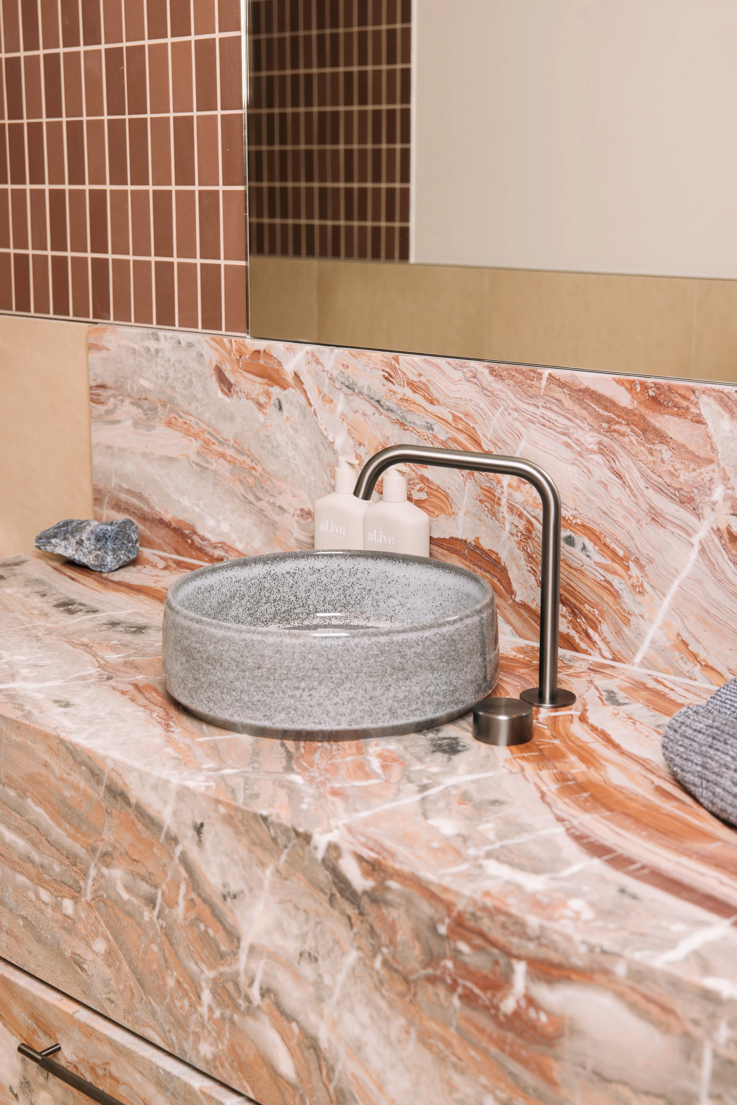 Round vessel basin on a warm veined stone vanity at Elixir Skin Fitness